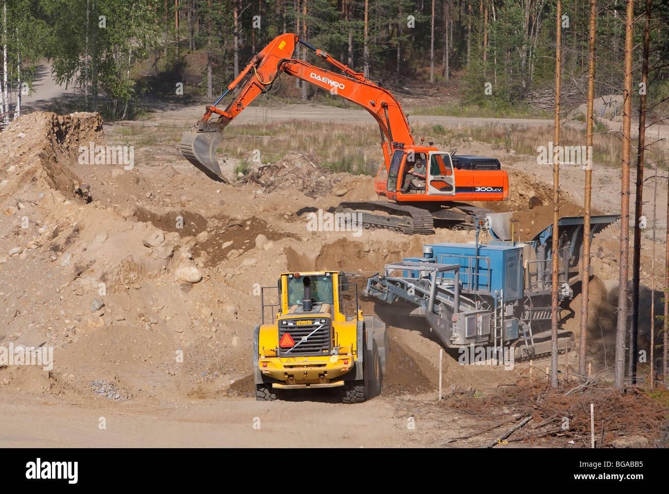 Produzione in sabbia finlandese; la scavatrice carica pietre al frantoio / separatore e il caricatore frontale preleva ghiaia nell'area di estrazione della sabbia, Finlan Foto Stock