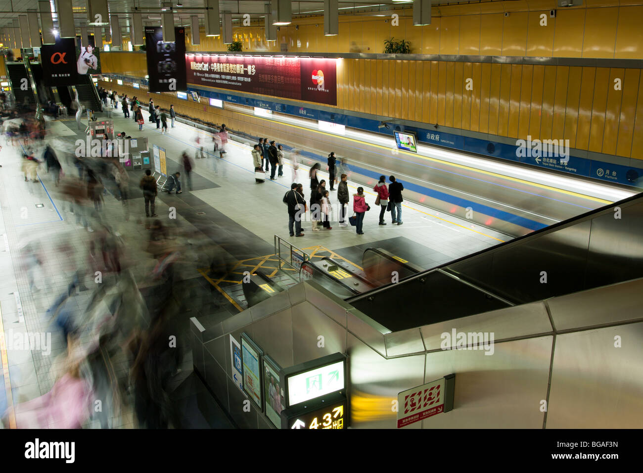 La gente aspetta, cammina sulla piattaforma della metropolitana della stazione della metropolitana di Taipei City Hall a Taiwan. Sfocatura di persone dinamiche in movimento, scatti a lunga esposizione Foto Stock