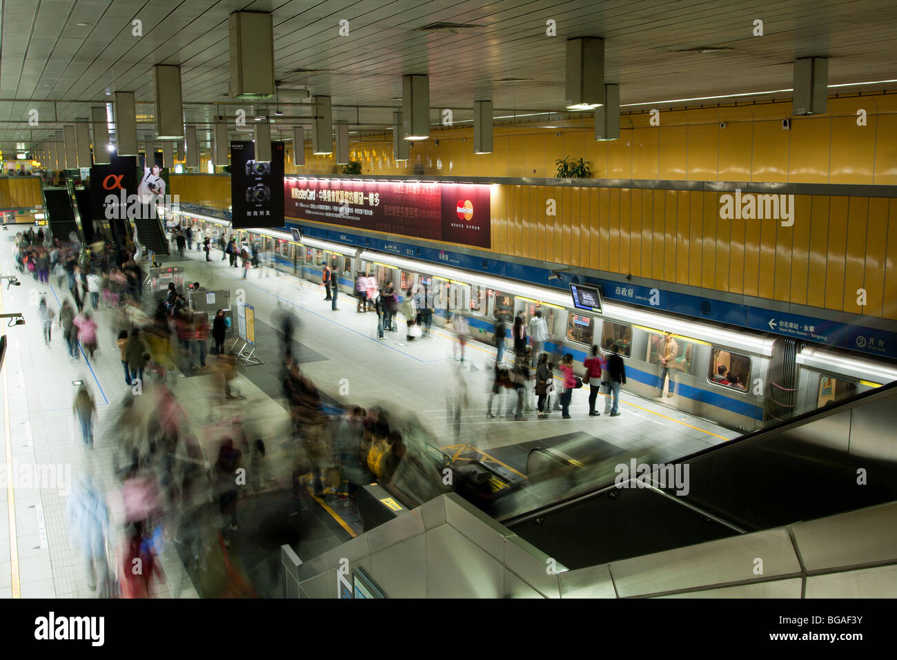 La gente aspetta, cammina sulla piattaforma della metropolitana della stazione della metropolitana di Taipei City Hall a Taiwan. Sfocatura di persone dinamiche in movimento, scatti a lunga esposizione Foto Stock