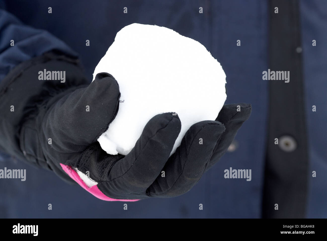 Mano che tiene palla di neve con la mano guantata e rivestire Foto Stock