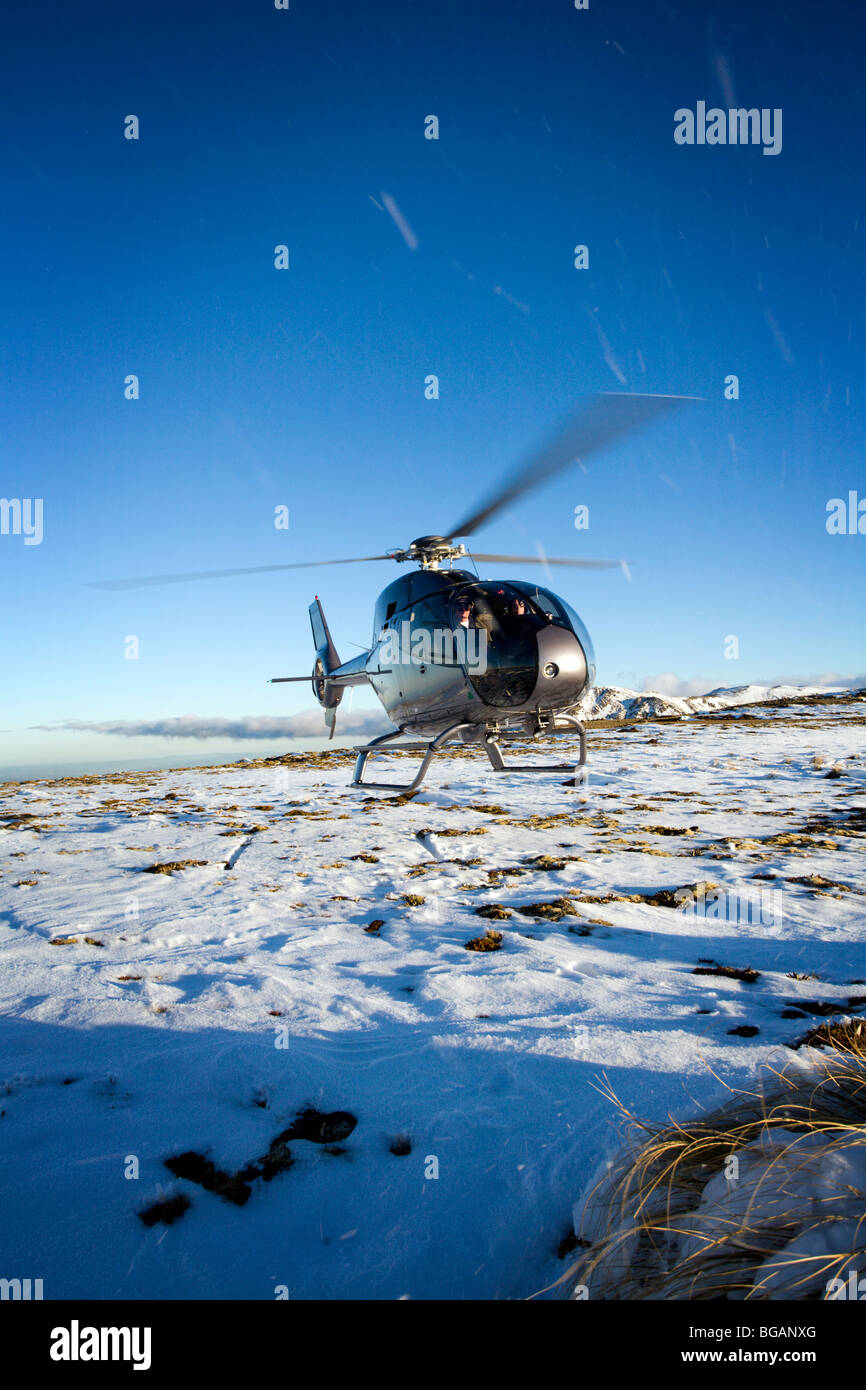 Elicottero in attesa di volare da neve top mountain con sunny blue skies Foto Stock
