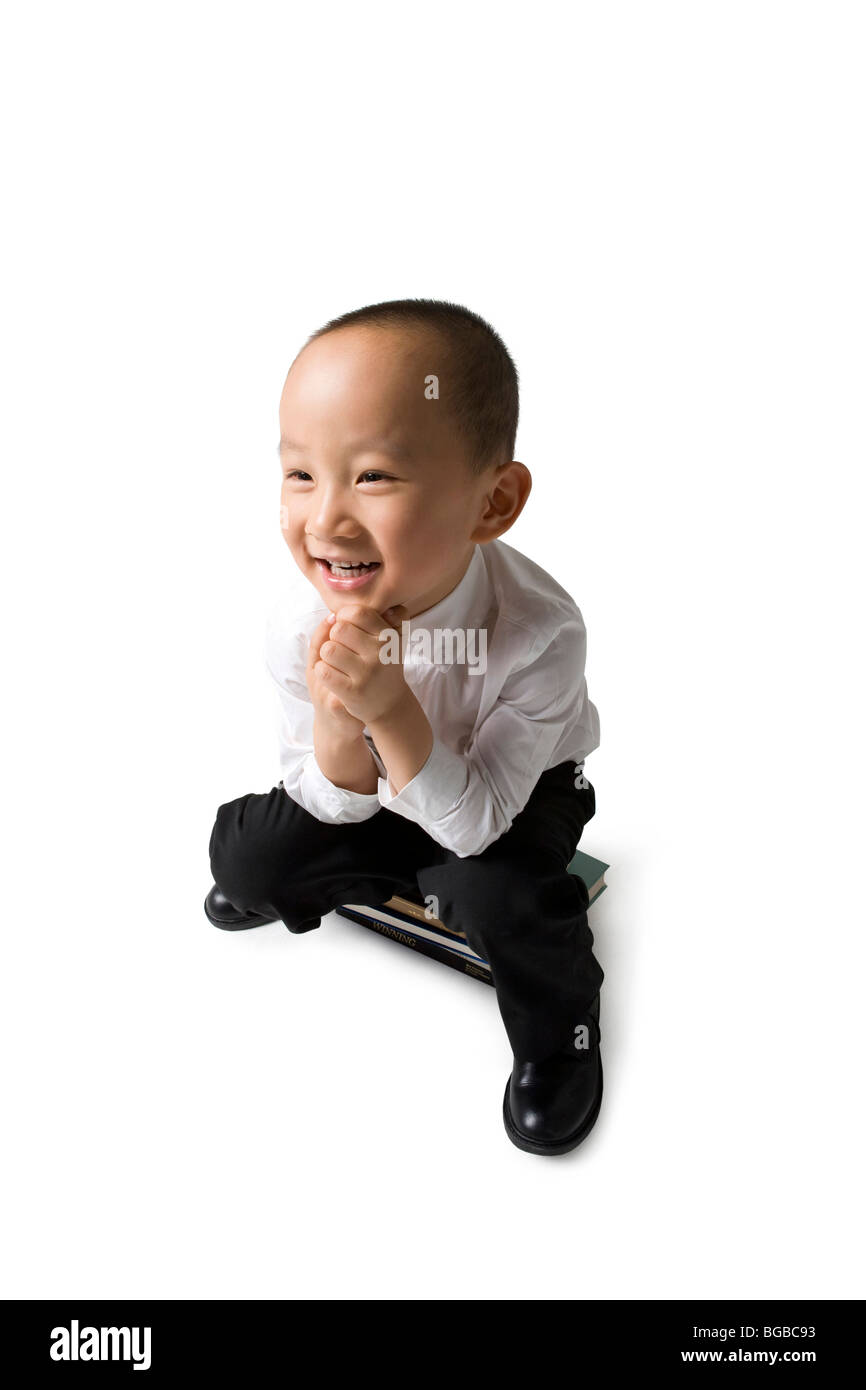 Ragazzo giovane si siede su alcuni libri Foto Stock