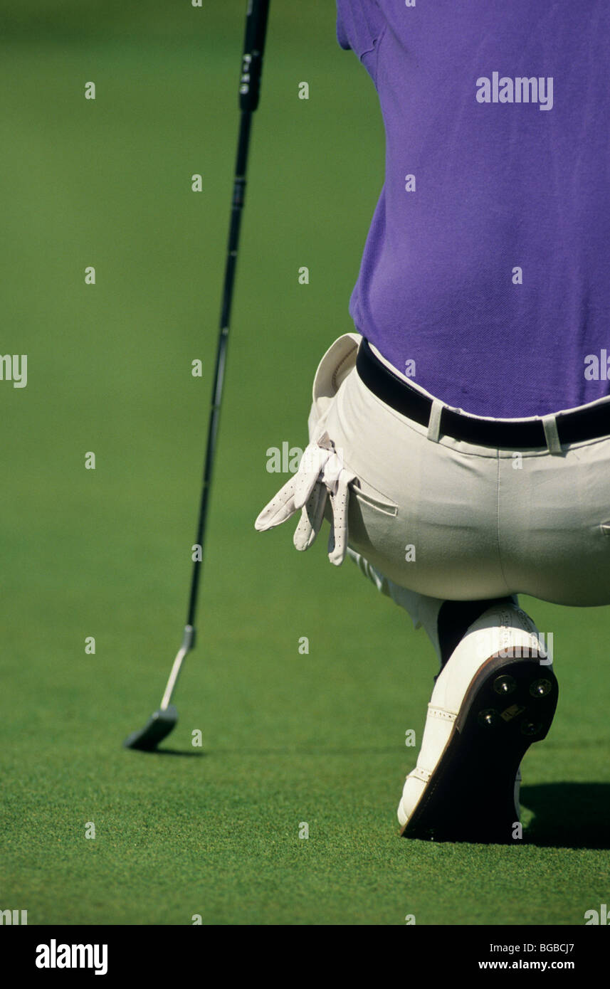 Il Golfer accucciato giù per analizzare la sua shot Foto Stock