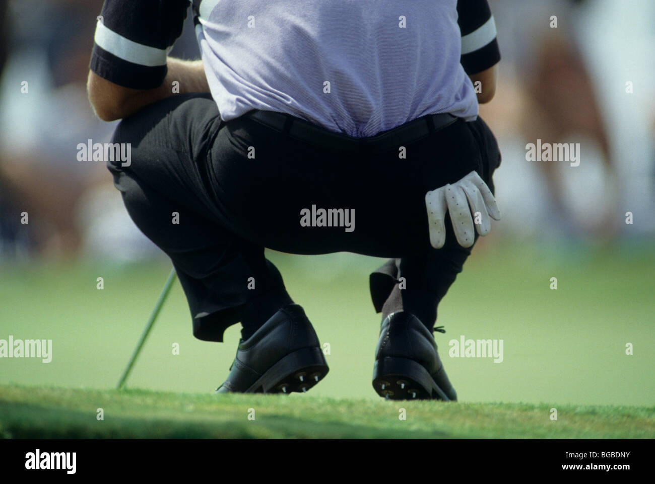 Il Golfer accucciato giù per analizzare la sua shot Foto Stock