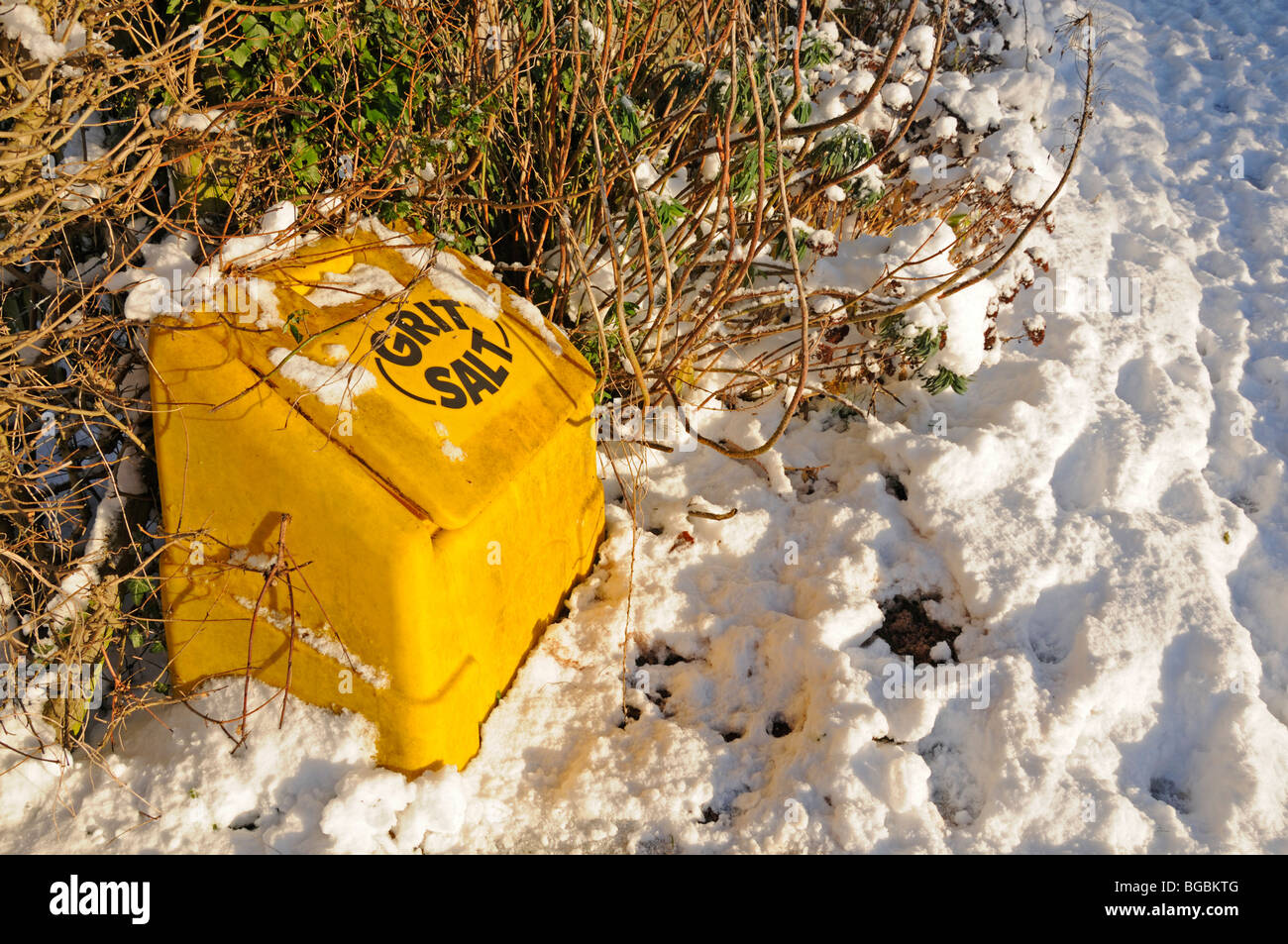 Graniglia sul ciglio della strada e il contenitore del sale nella neve. Kent, Regno Unito Foto Stock