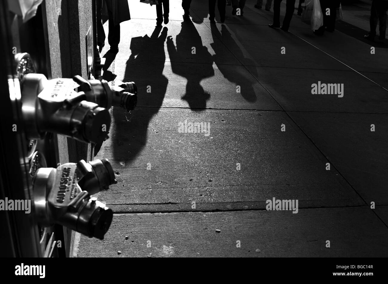 Christmas Shopper gettato ombre lunghe come essi camminare lungo la Quinta Avenue Midtown Manhattan New York STATI UNITI D'AMERICA - Foto di Simon Dack Foto Stock
