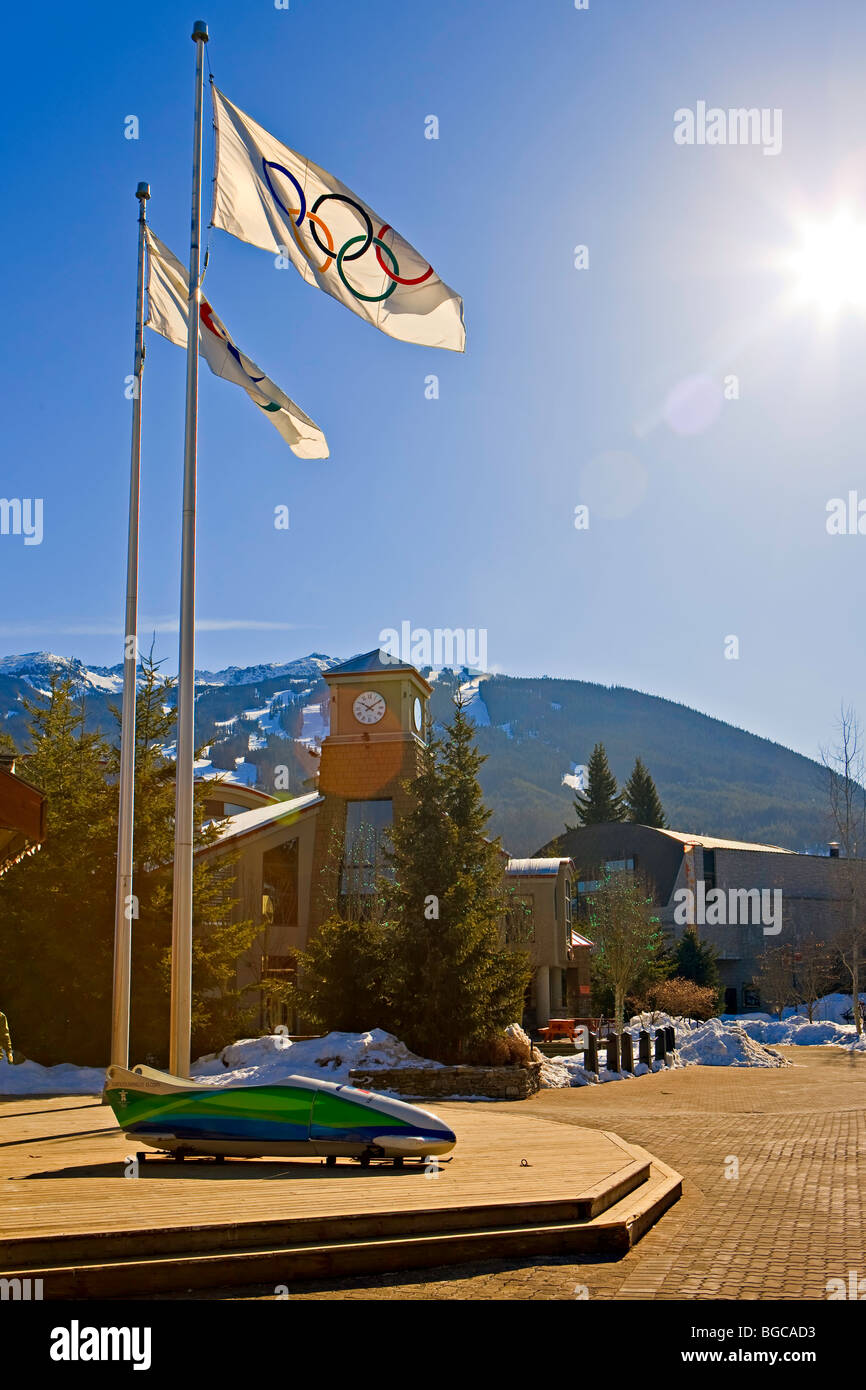 Olympic bandiere e Bob al di fuori del 2010 ufficio Giochi Olimpici lungo la passeggiata del villaggio accanto ai tini di filtrazione in Whistler Village wit Foto Stock