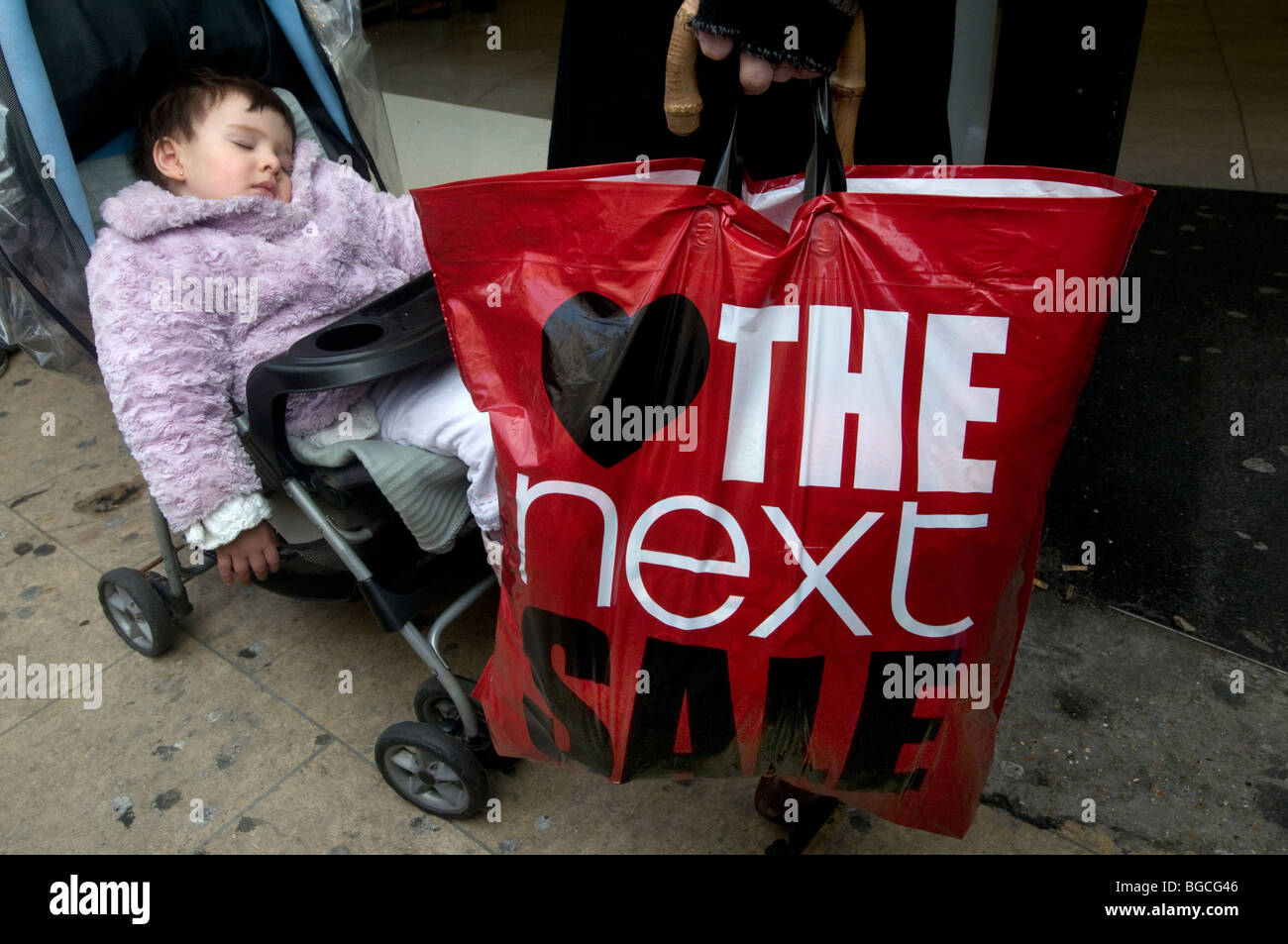 Oxford street , Boxing day 2009 Vendite.il bambino dorme in un passeggino accanto al padre con la prossima vendita borsa. Foto Stock