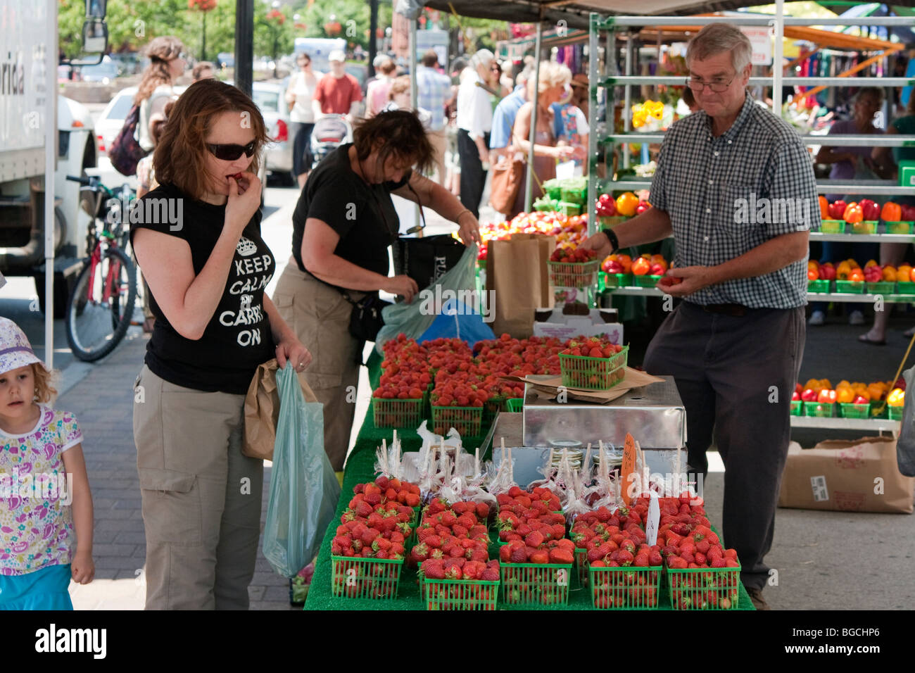 La donna il campionamento di una fragola al mercato del contadino, il Mercato di San Lorenzo, Toronto, Canada Foto Stock