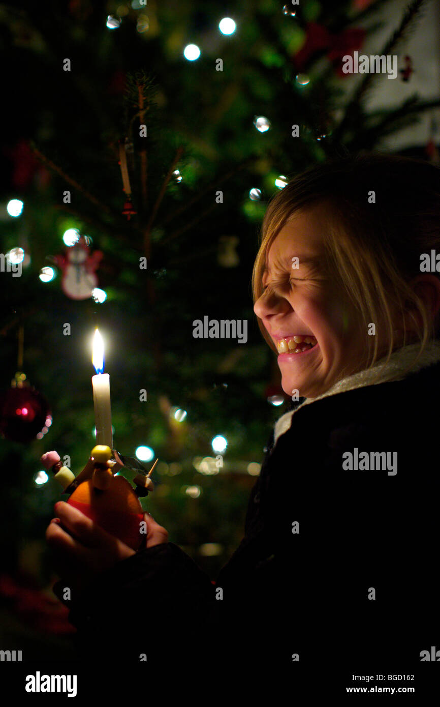 Giovane ragazza tenendo un Christingle a Carol service a Natale Foto Stock