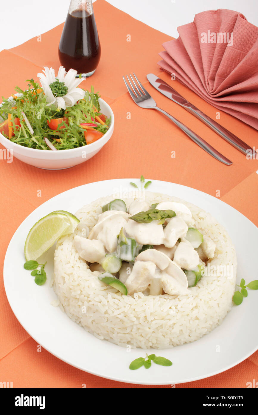 Fricassea di pollo con funghi e asparagi verdi circondate da un confine di riso, insalata mista Foto Stock