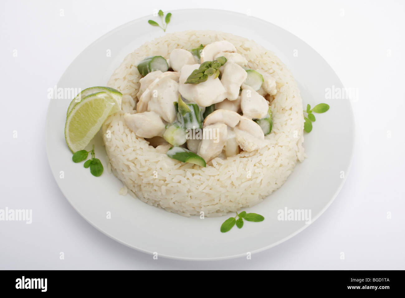 Fricassea di pollo con funghi e asparagi verdi circondate da un confine di riso Foto Stock