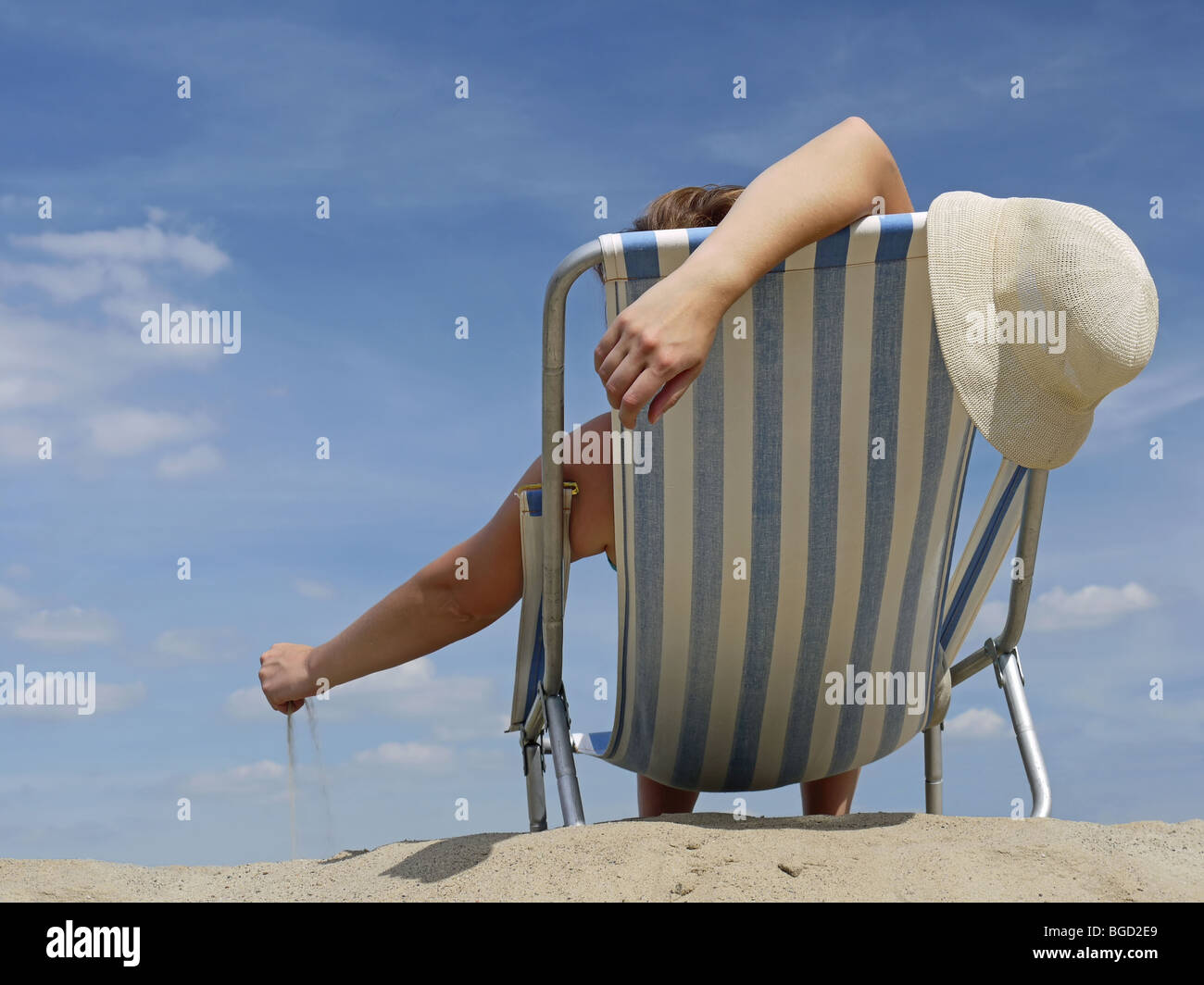 Donna rilassante sulla spiaggia sulla sdraio a giocare con sabbia Foto Stock