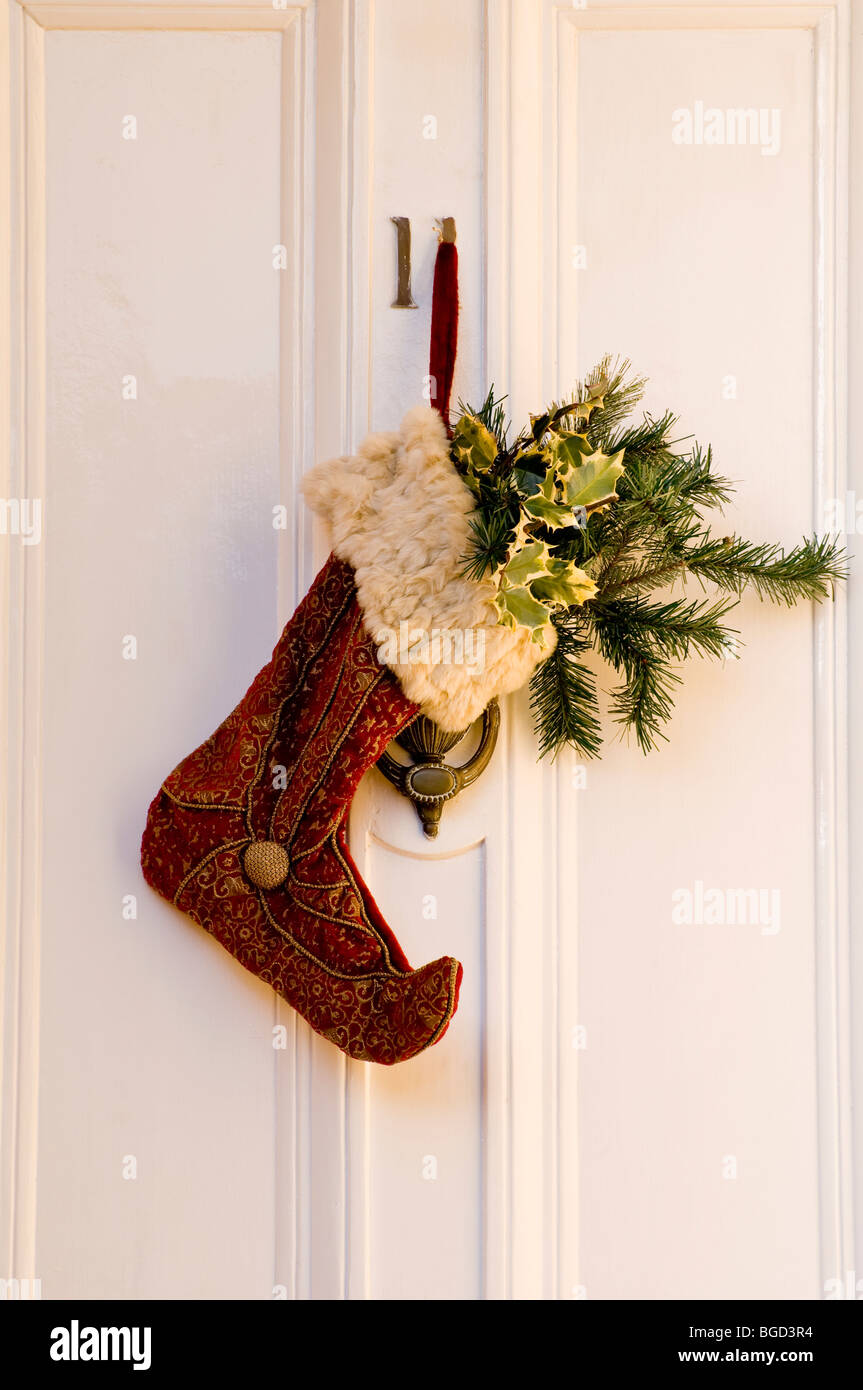 Bella dettagliata e una texture ricca Calza di Natale e Holly su un Regency English Cotswold Town House porta. Foto Stock