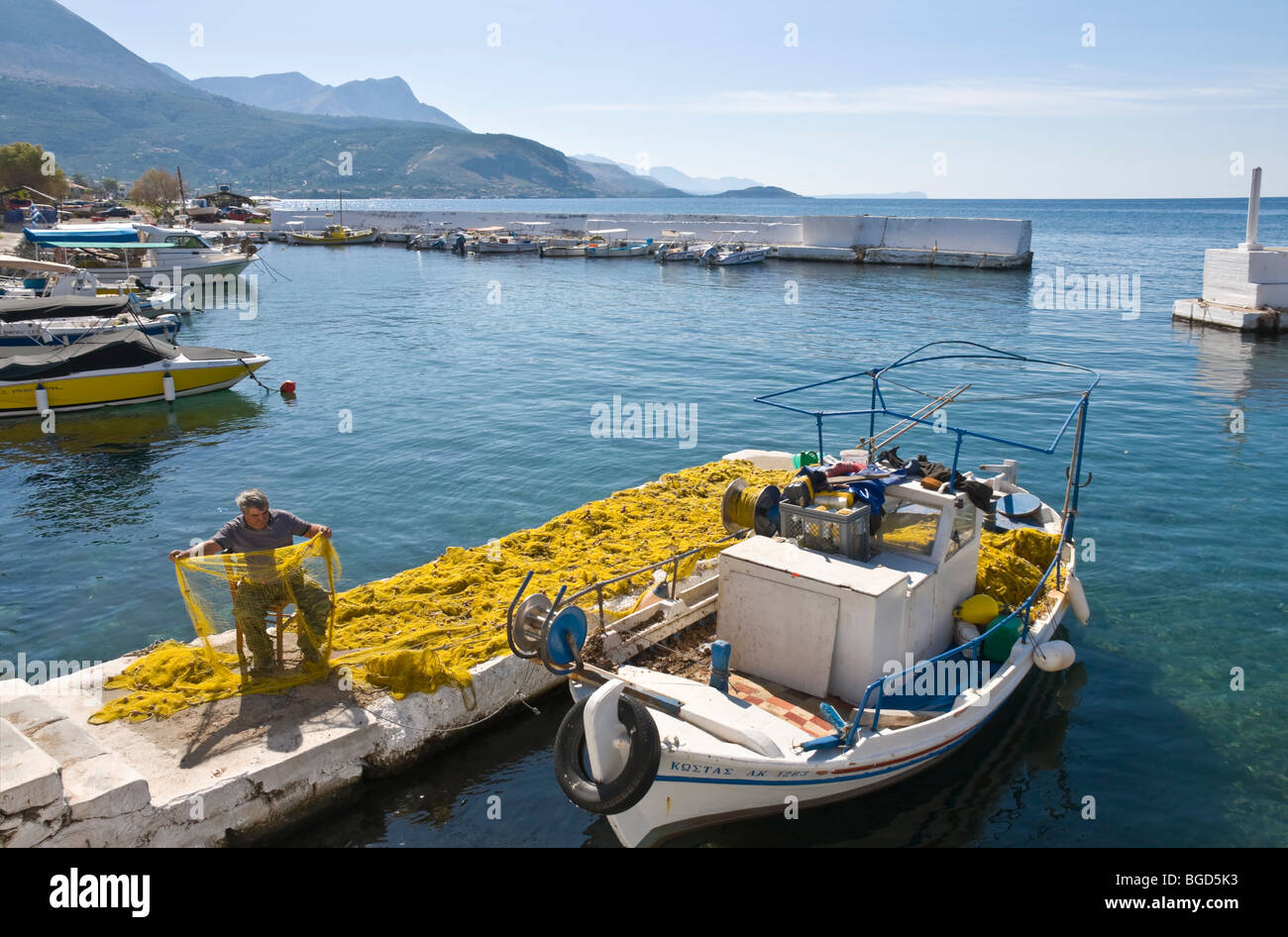Un pescatore riassettavano le reti nel piccolo porto di Aghios Nikolaos, nella parte esterna di Mani, sud del Peloponneso, della Grecia. Foto Stock