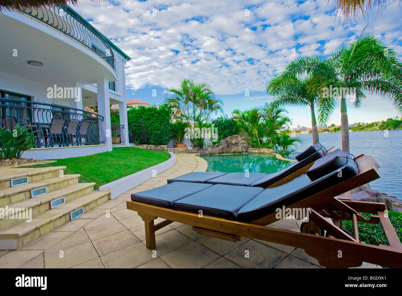 Sedie a sdraio in piscina a waterfront mansion Foto Stock