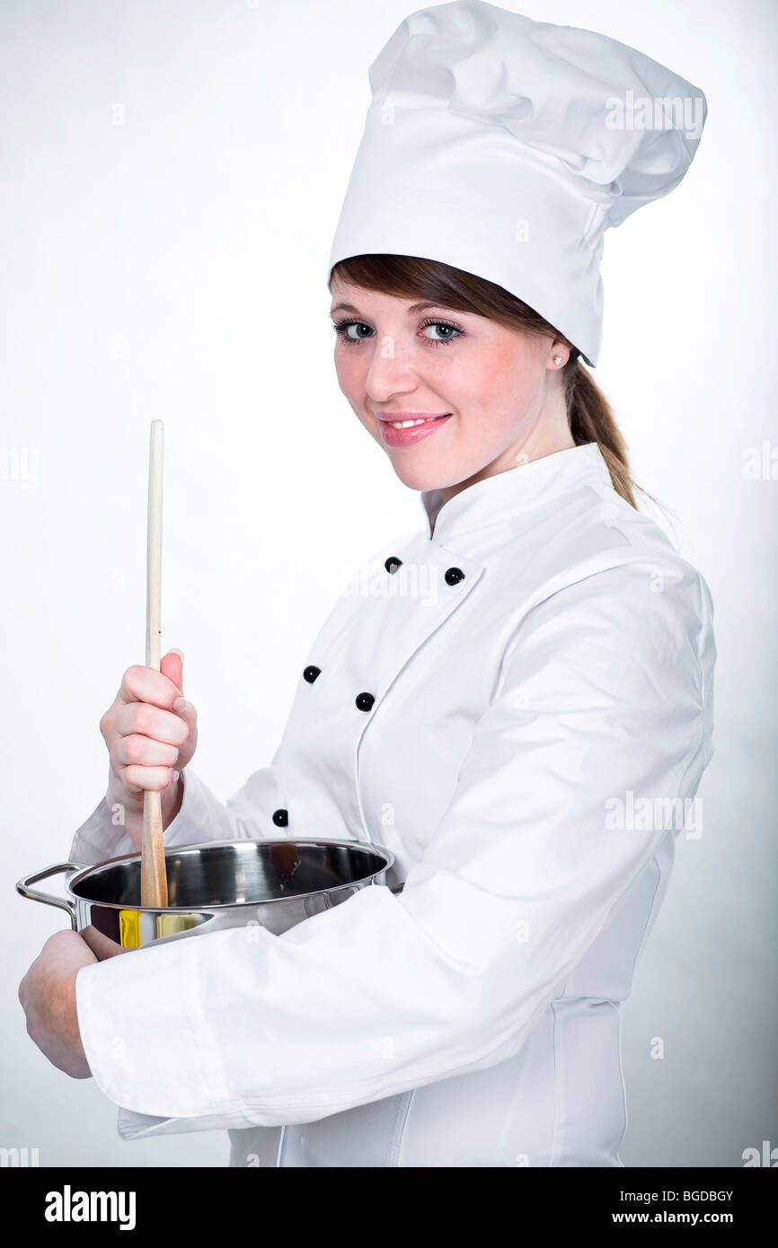 Il giovane chef con il cucchiaio di legno e la pentola di cottura Foto Stock