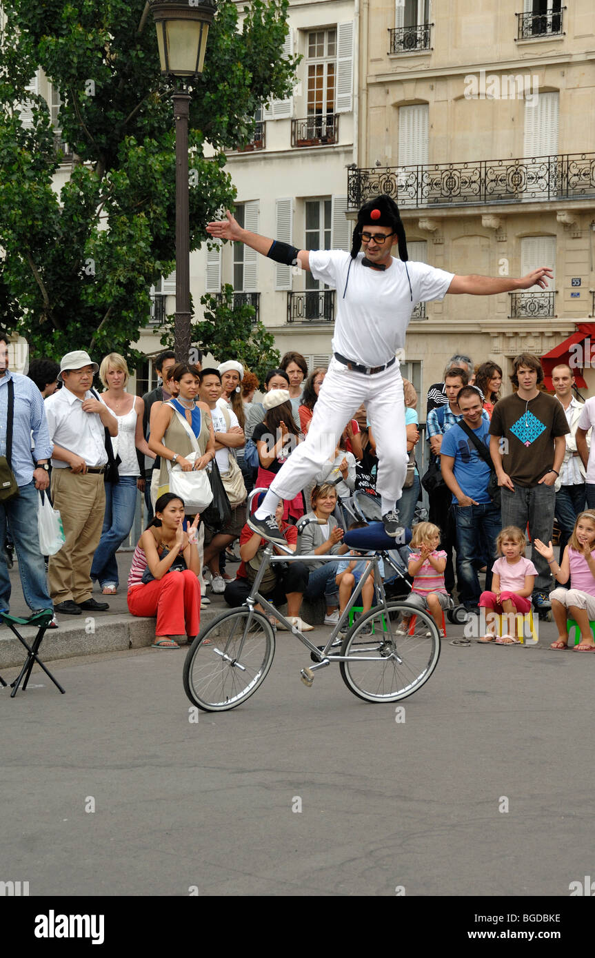 Street Theatre, Street Performer o Street Entertainer Balancing on Bicycle, Pont Saint Louis, Île Saint Louis, Parigi, Francia Foto Stock