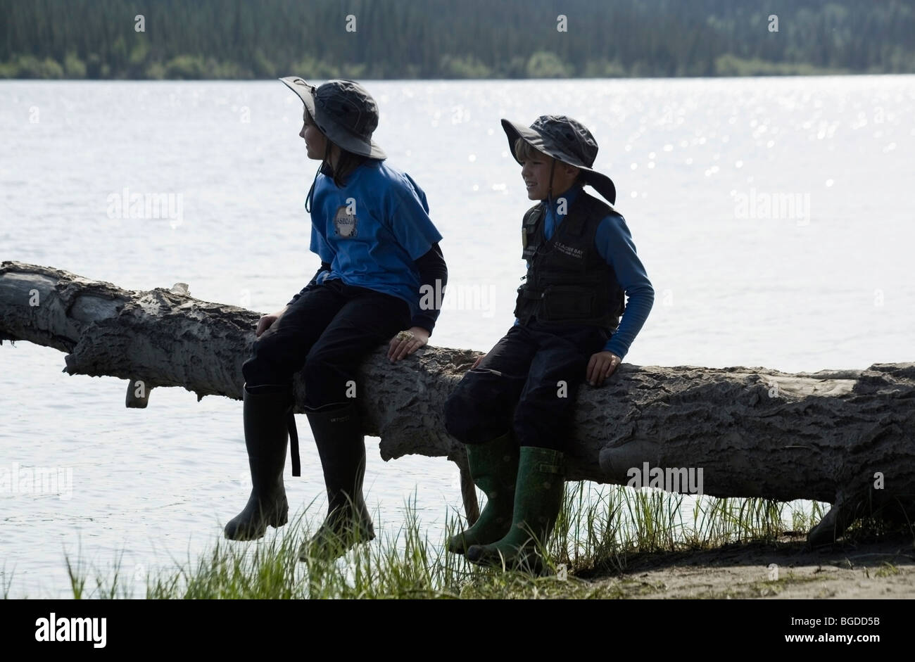 In vacanza, fratelli, 12 anno vecchia ragazza e 6 anno vecchio ragazzo seduto su un tronco di albero, Teslin River, Yukon Territory, Canada Foto Stock