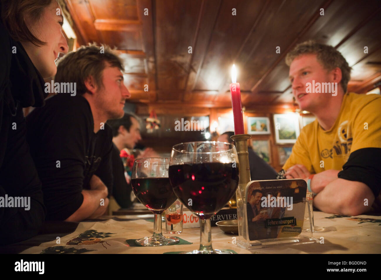 Giovani sat di bere vino rosso intorno a un tavolo in 'La metropolitana' apres ski bar in St Anton am Arlberg, Austria, l'Europa. Foto Stock