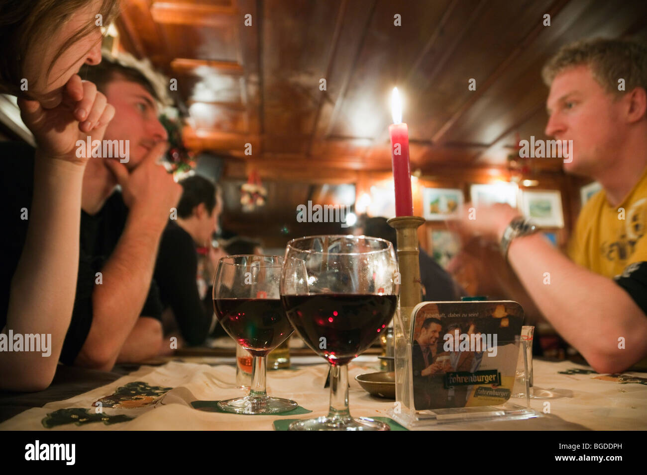 Hygge quotidiana scena di giovani sat bevendo vino intorno a un tavolo in un bar. Lo stile di vita moderno. L'Austria, l'Europa. Foto Stock