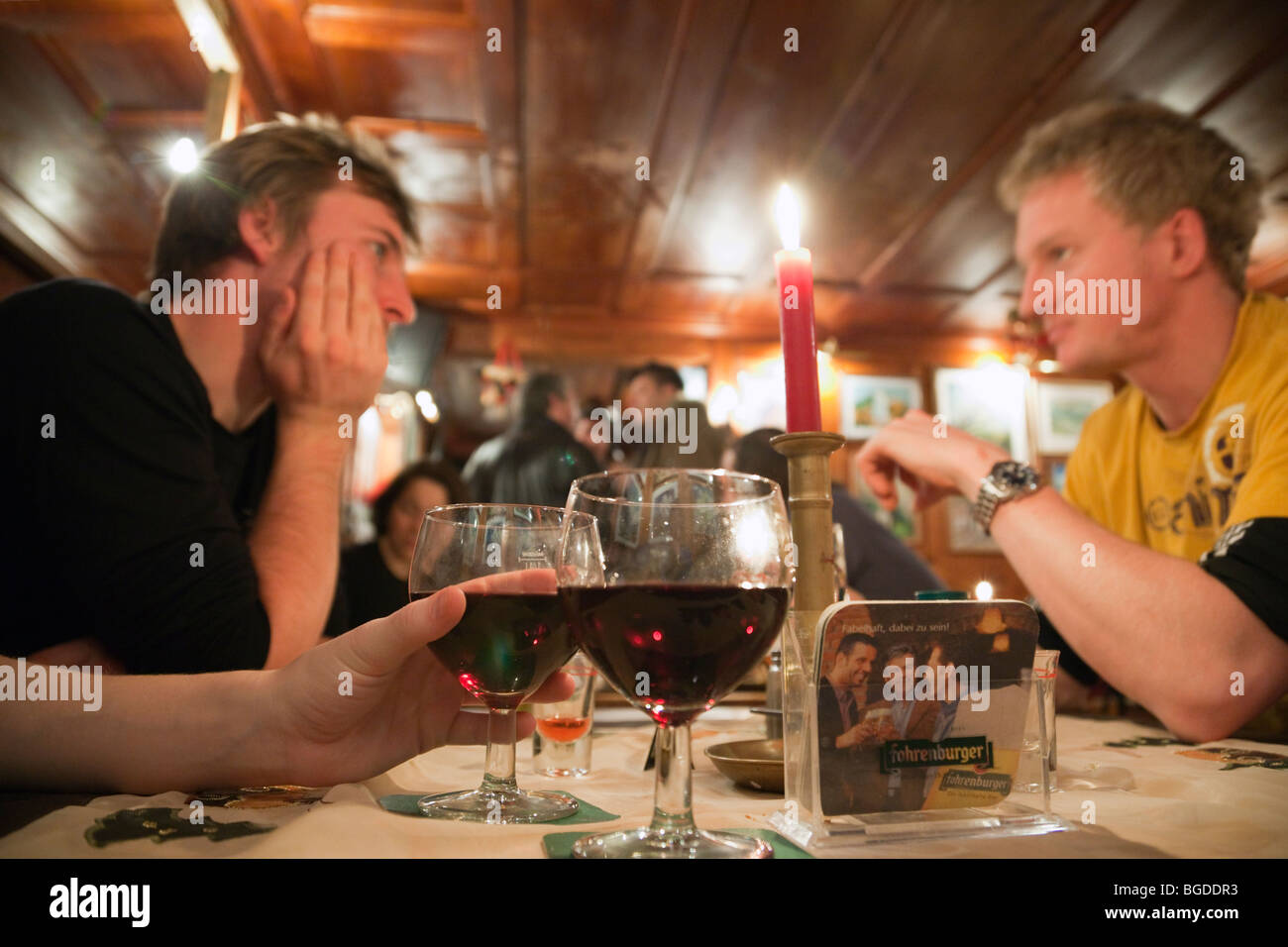 Giovani sat bevendo vino intorno a un tavolo in un apres ski bar. Lo stile di vita moderno. St Anton, Austria, l'Europa. Foto Stock