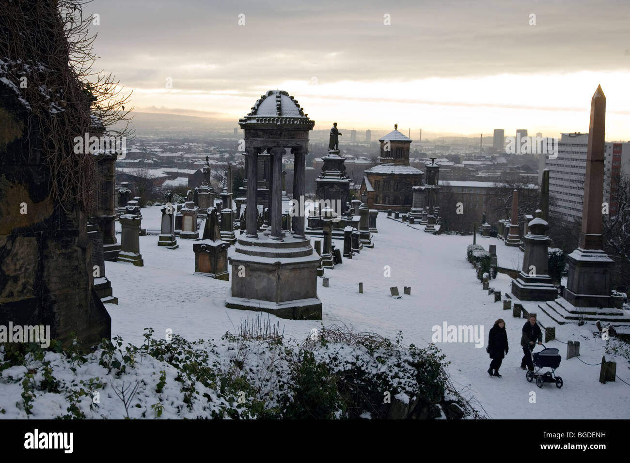 Una famiglia spingere un passeggino attraverso la necropoli di Glasgow sotto la neve in inverno 2009 Foto Stock