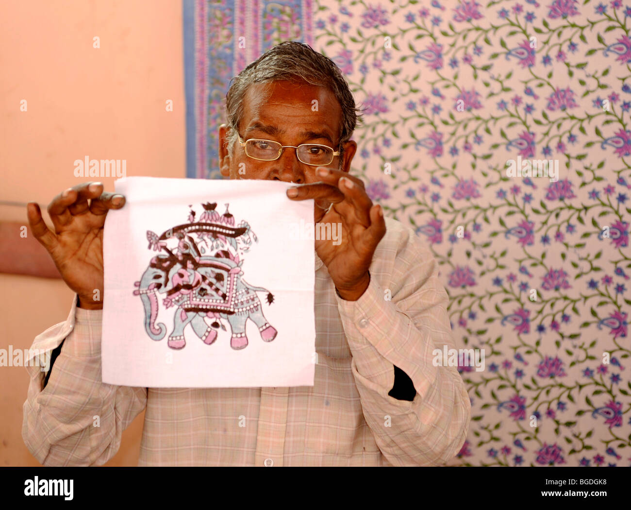 Indian uomo presentando il modello del timbro di un elefante in un tappeto e coperta in fabbrica, Jaipur, Rajasthan, Nord India, India, Foto Stock