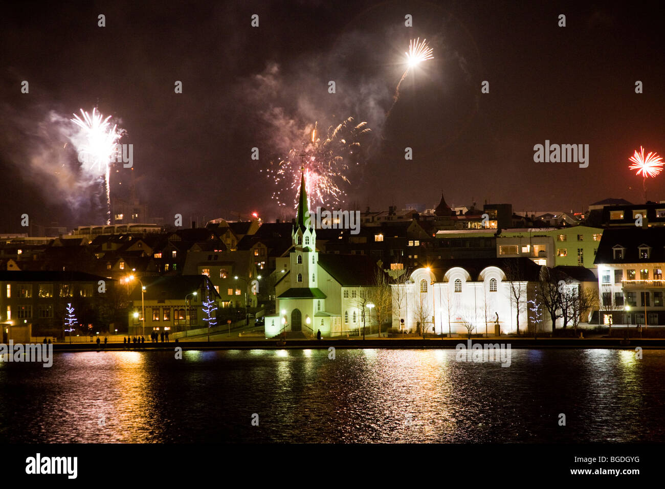 Il veglione di Capodanno fuochi d'artificio a mezzanotte. Il centro di Reykjavik, Islanda. Chiesa Frikirkjan (C) e la Galleria Nazionale dell'Islanda (R). Foto Stock