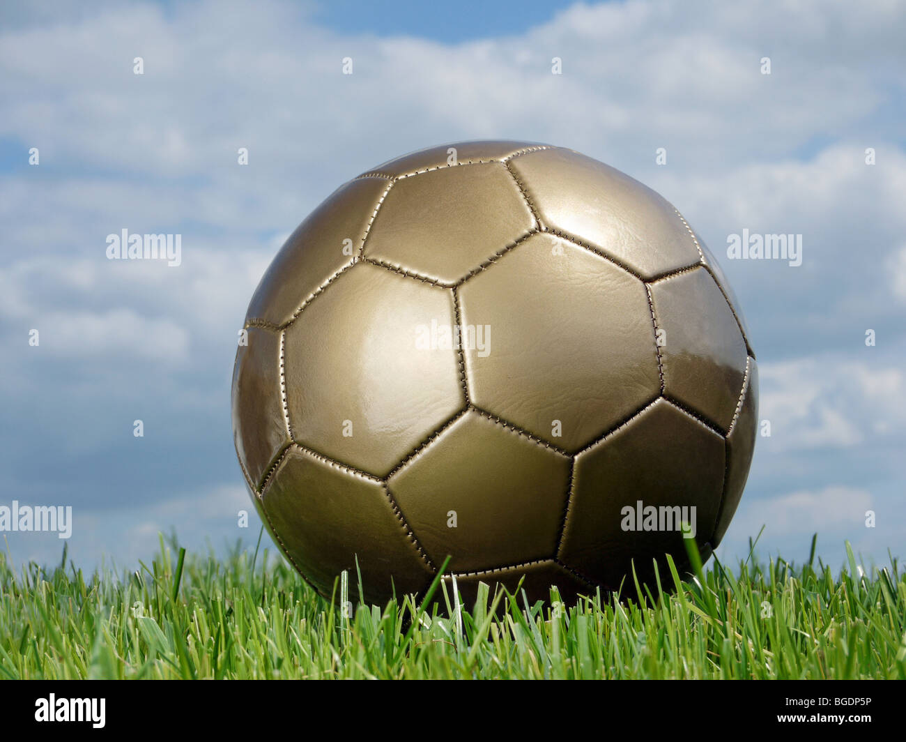 Golden Pallone da calcio in erba sparato contro il cielo Foto Stock