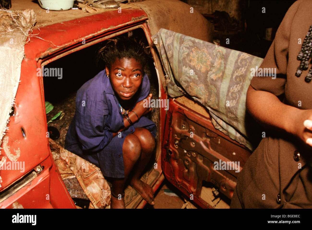 Ragazza senzatetto che vivono in una vettura di dumping è incoraggiato ad entrare a far parte di una classe di notte da un locale di carità, Luanda, Angola Foto Stock