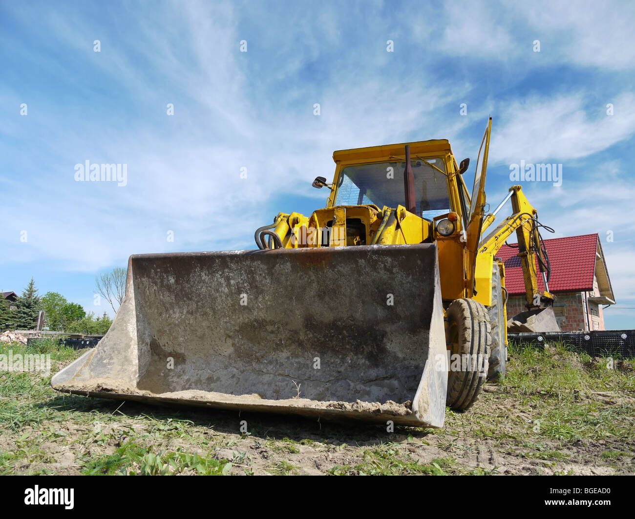 Il giallo il retroescavatore caricatore parcheggiato al sito in costruzione Foto Stock
