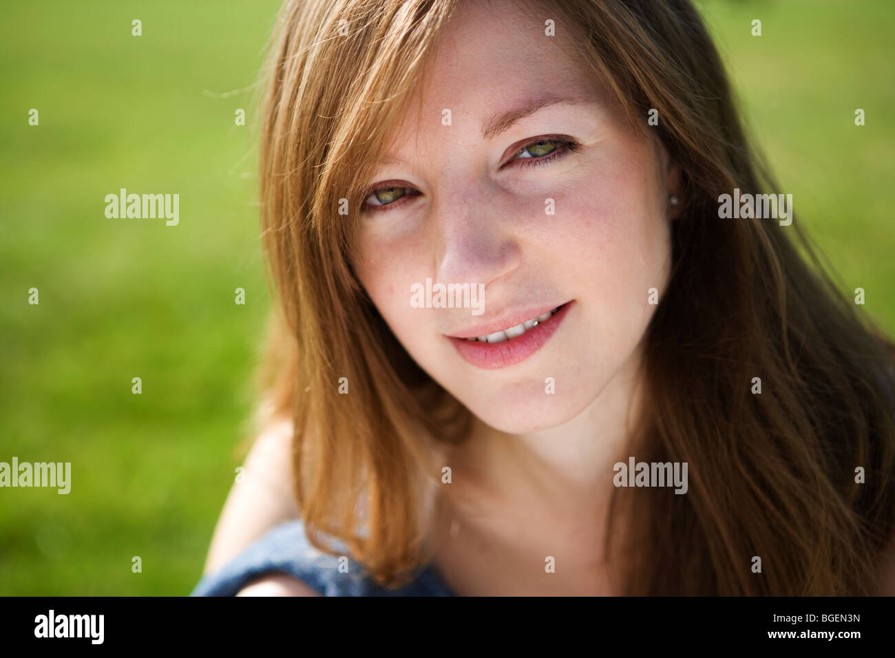 Outdoor closeup Ritratto di giovane donna seduta sull'erba. Foto Stock