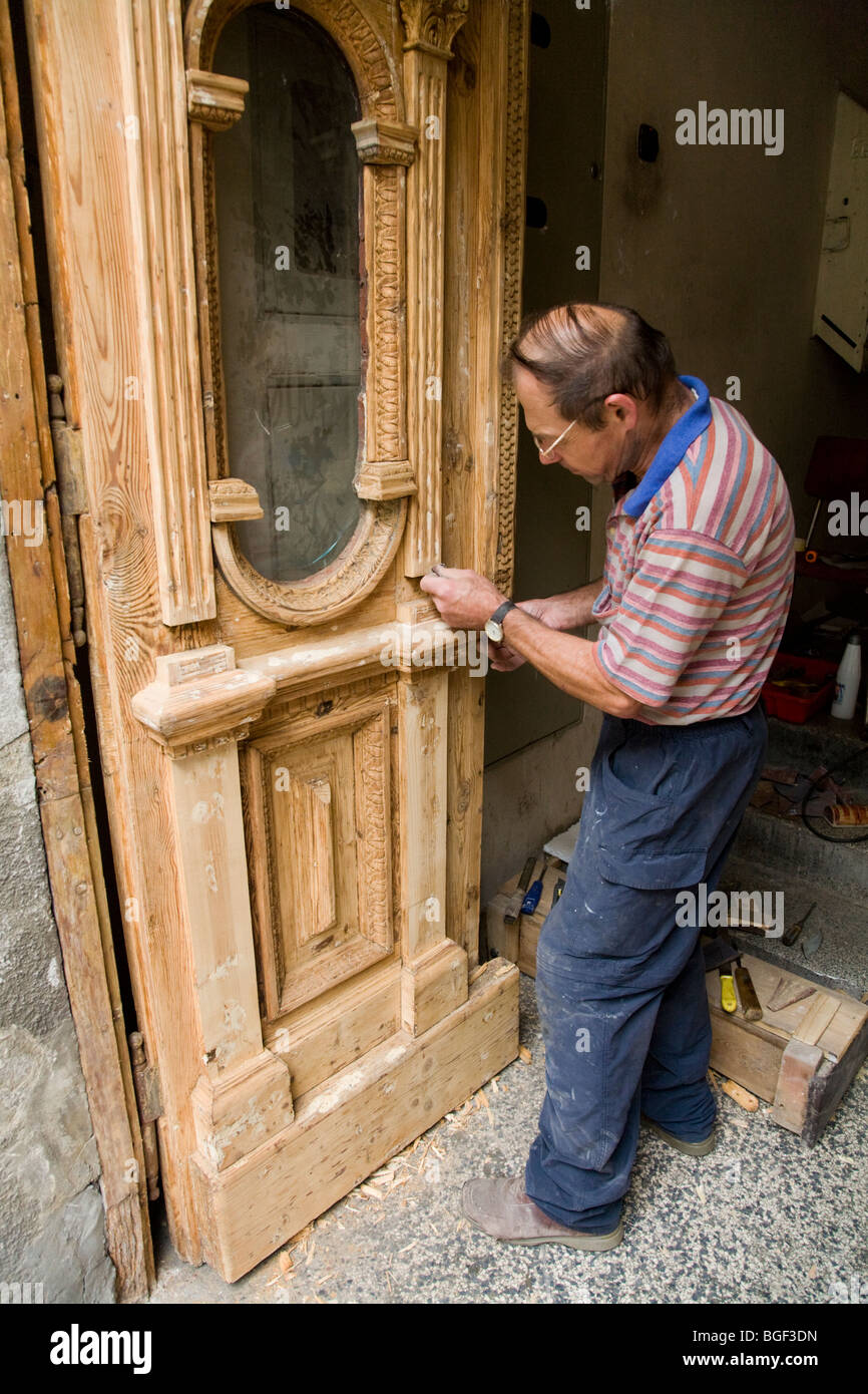 L'uomo polacco sul lavoro il ripristino di una vecchia porta di legno in una proprietà a Cracovia centro città. La Polonia. Foto Stock