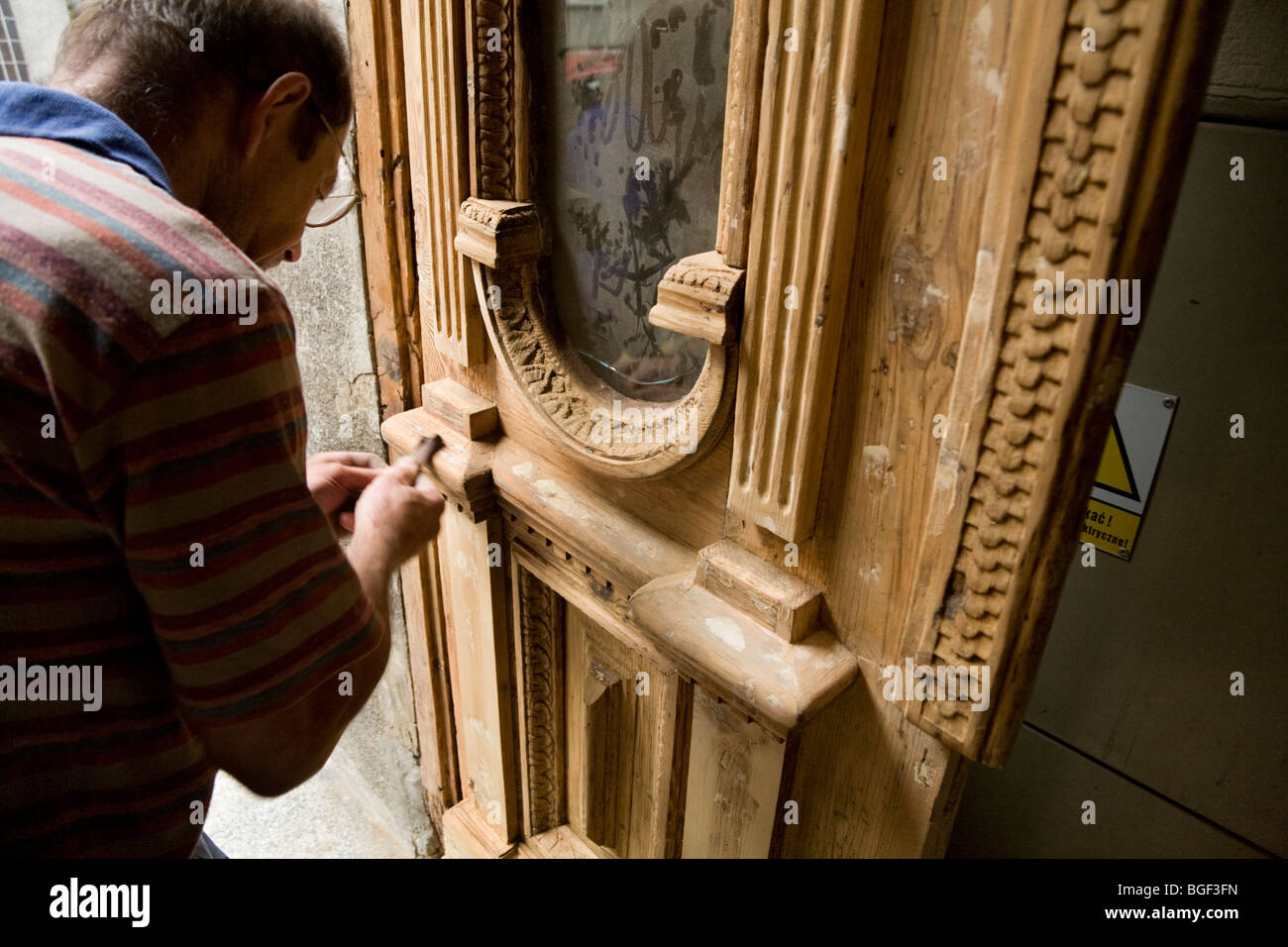 L'uomo polacco sul lavoro il ripristino di una vecchia porta di legno in una proprietà a Cracovia centro città. La Polonia. Foto Stock