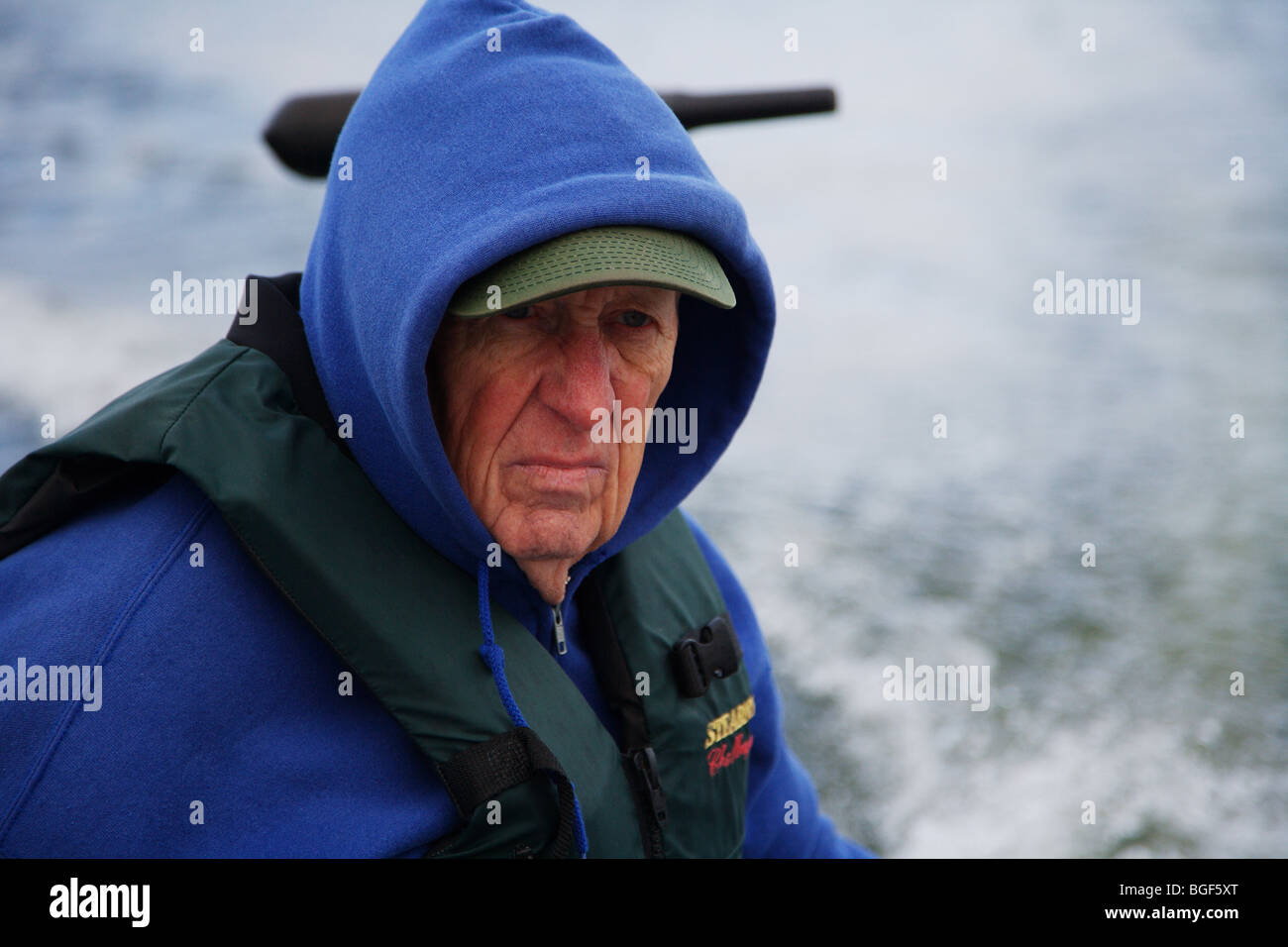 Senior anziani condito guida di pesca la guida alumnacraft barca da pesca nel freddo umido meteo instabile acqua onde wake azione Foto Stock
