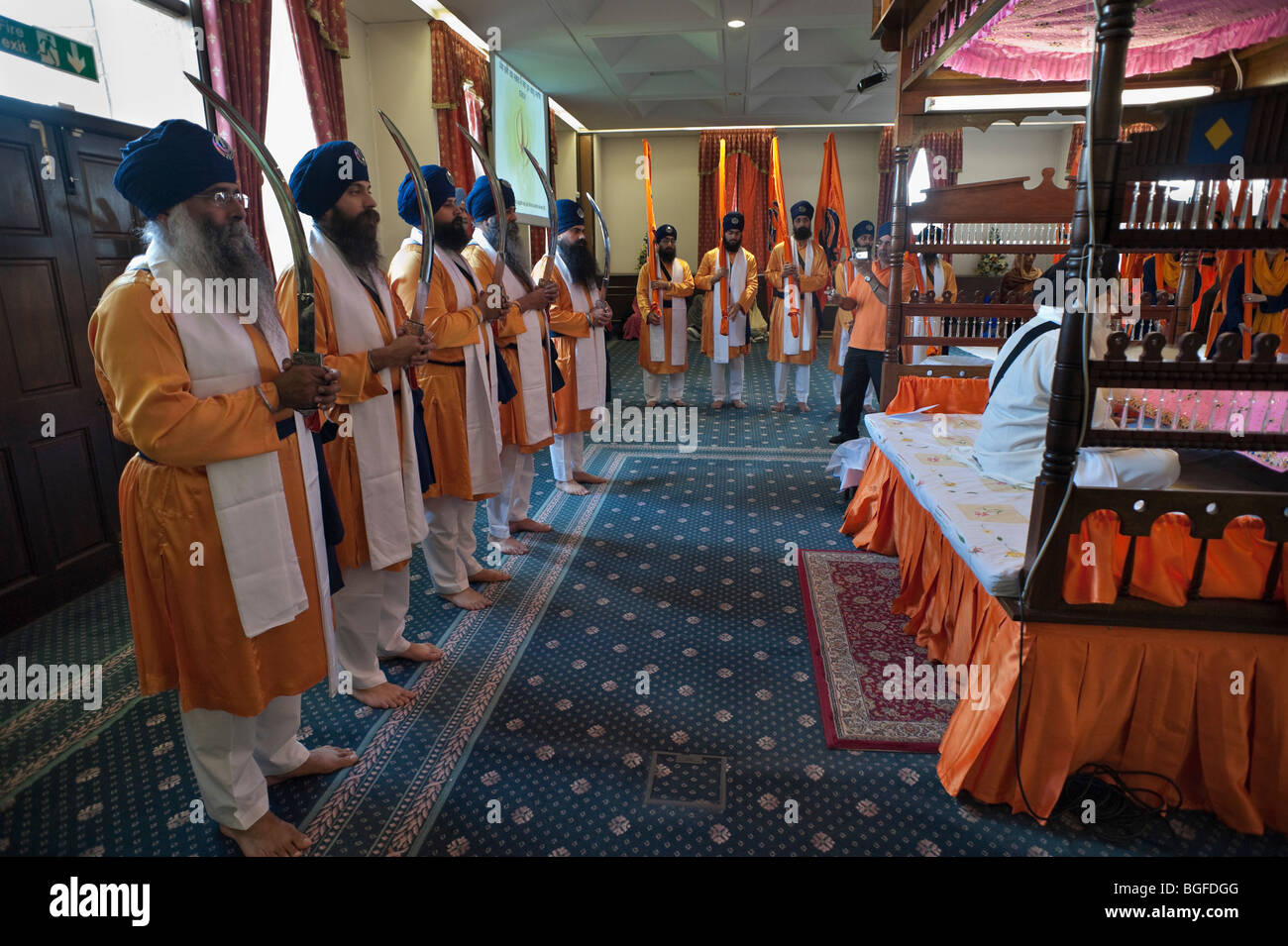 Il Panj Pyare e Sikh alfieri di sostare dietro il Guru Granth Sahib nella sala culto durante le celebrazioni Vaisakhi Foto Stock