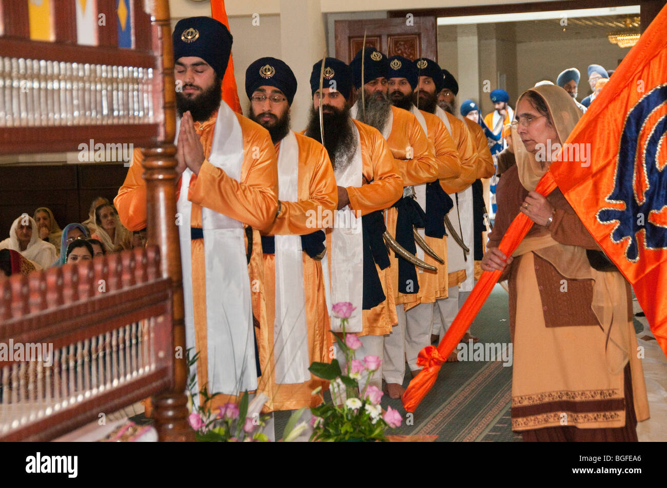 Il Panj Piyare linea fino a mostrare rispetto per il Guru Granth Sahib nel Diwan hall e una donna tiene un Nisan Sahib Foto Stock