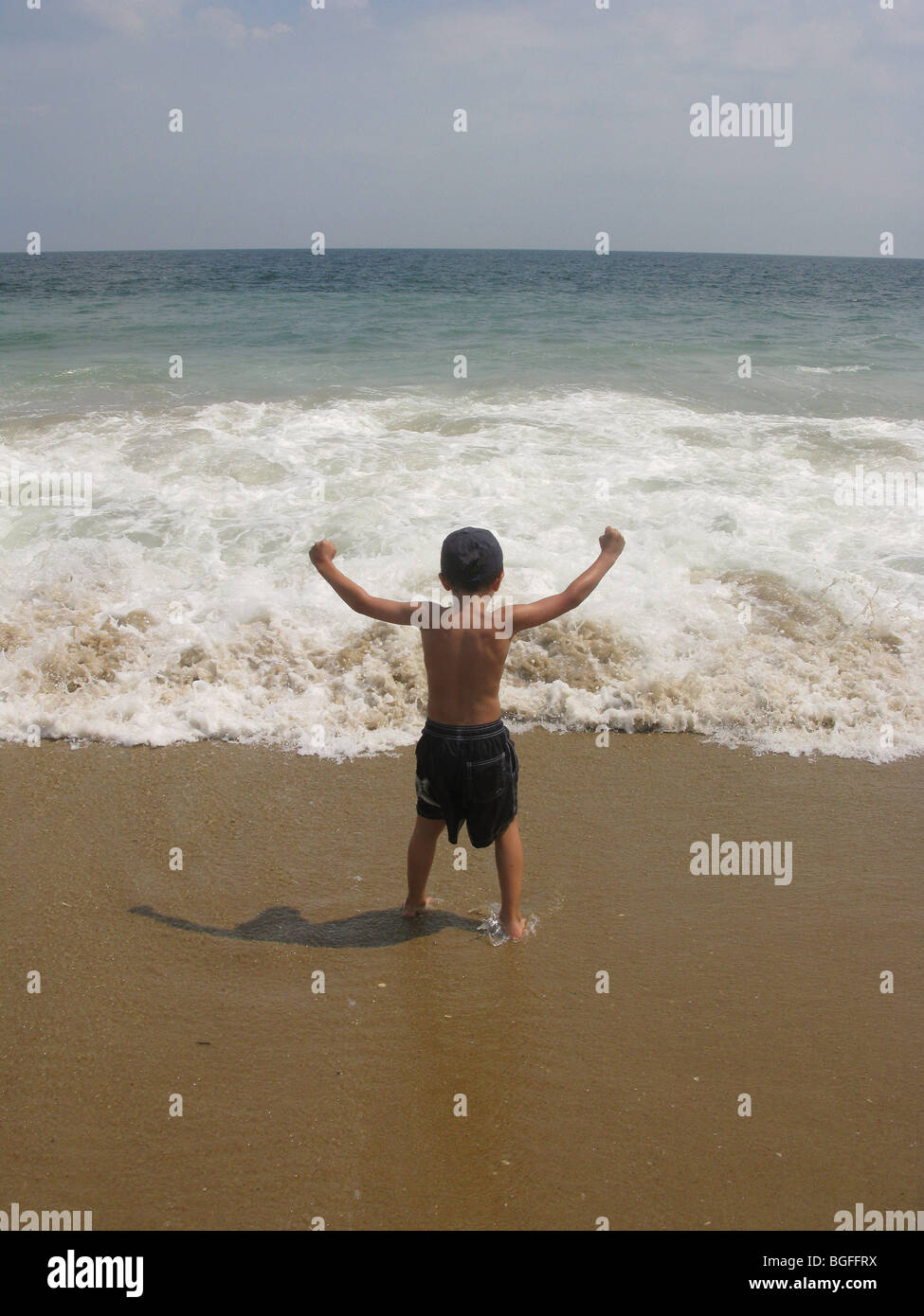Un giovane ragazzo sul bordo della spiaggia di onde di acqua Foto Stock