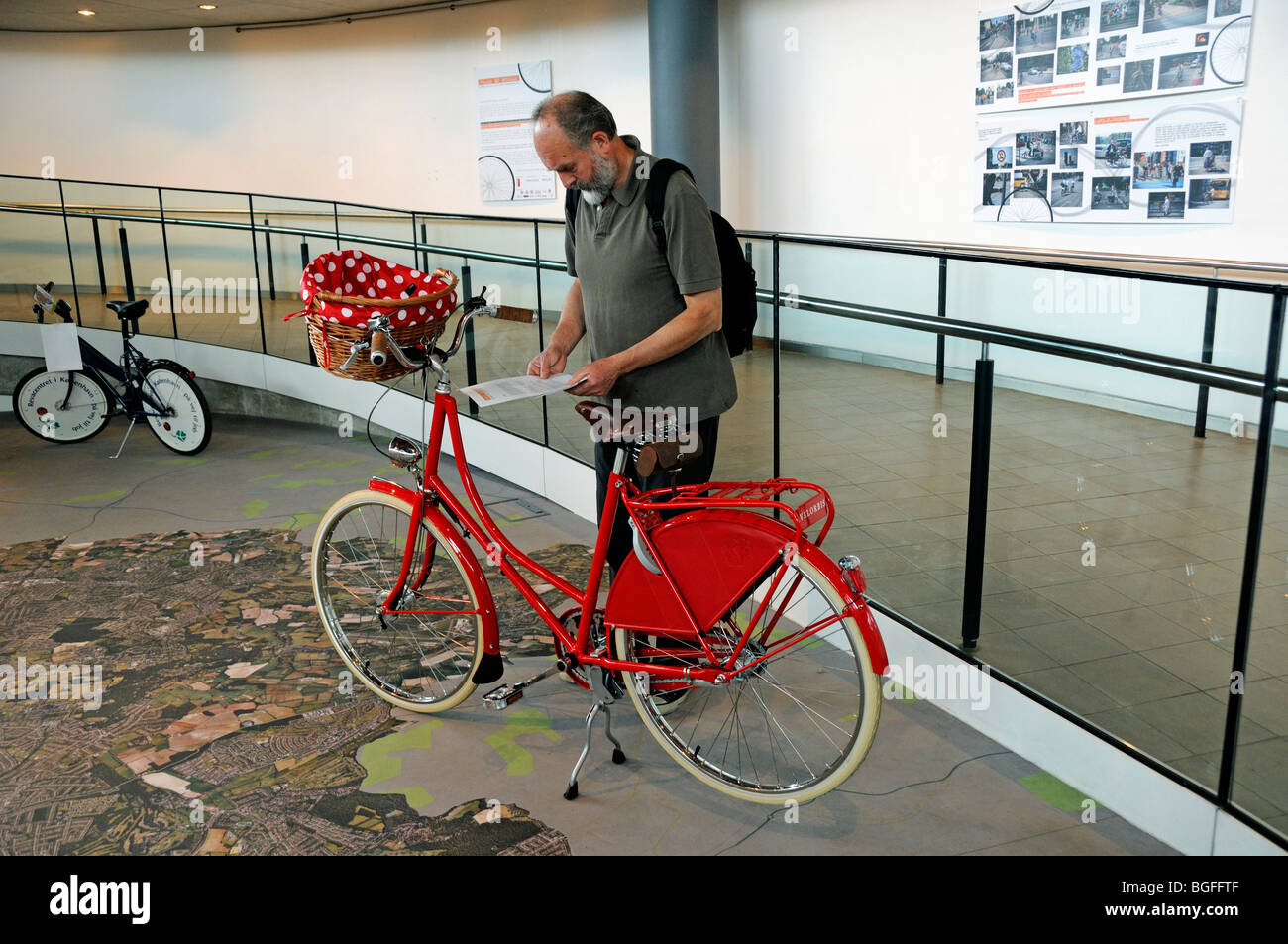 Uomo che guarda un signore rosso passo attraverso bike Foto Stock