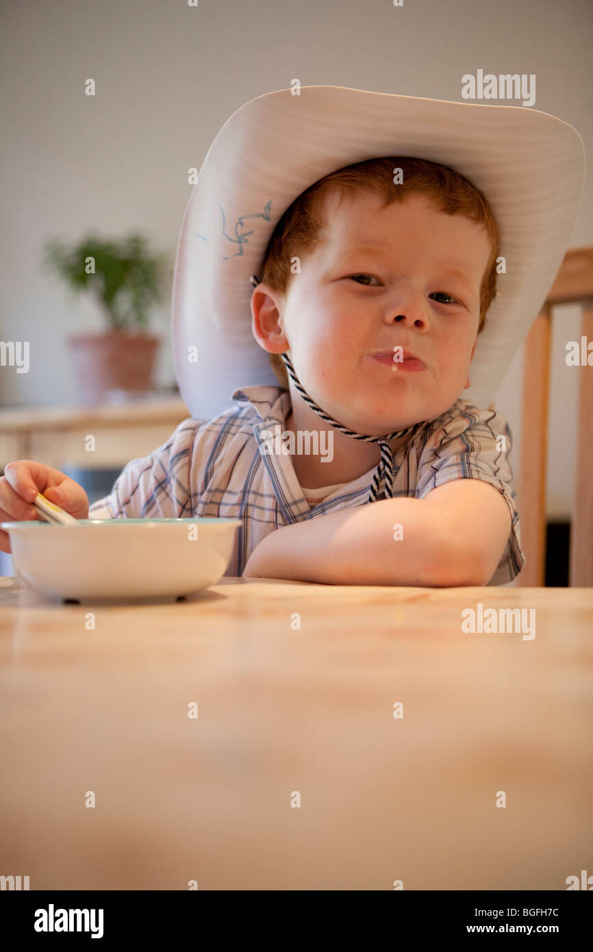 Un bambino di cinque anni, ragazzo di mangiare il suo cereale a colazione. Foto Stock
