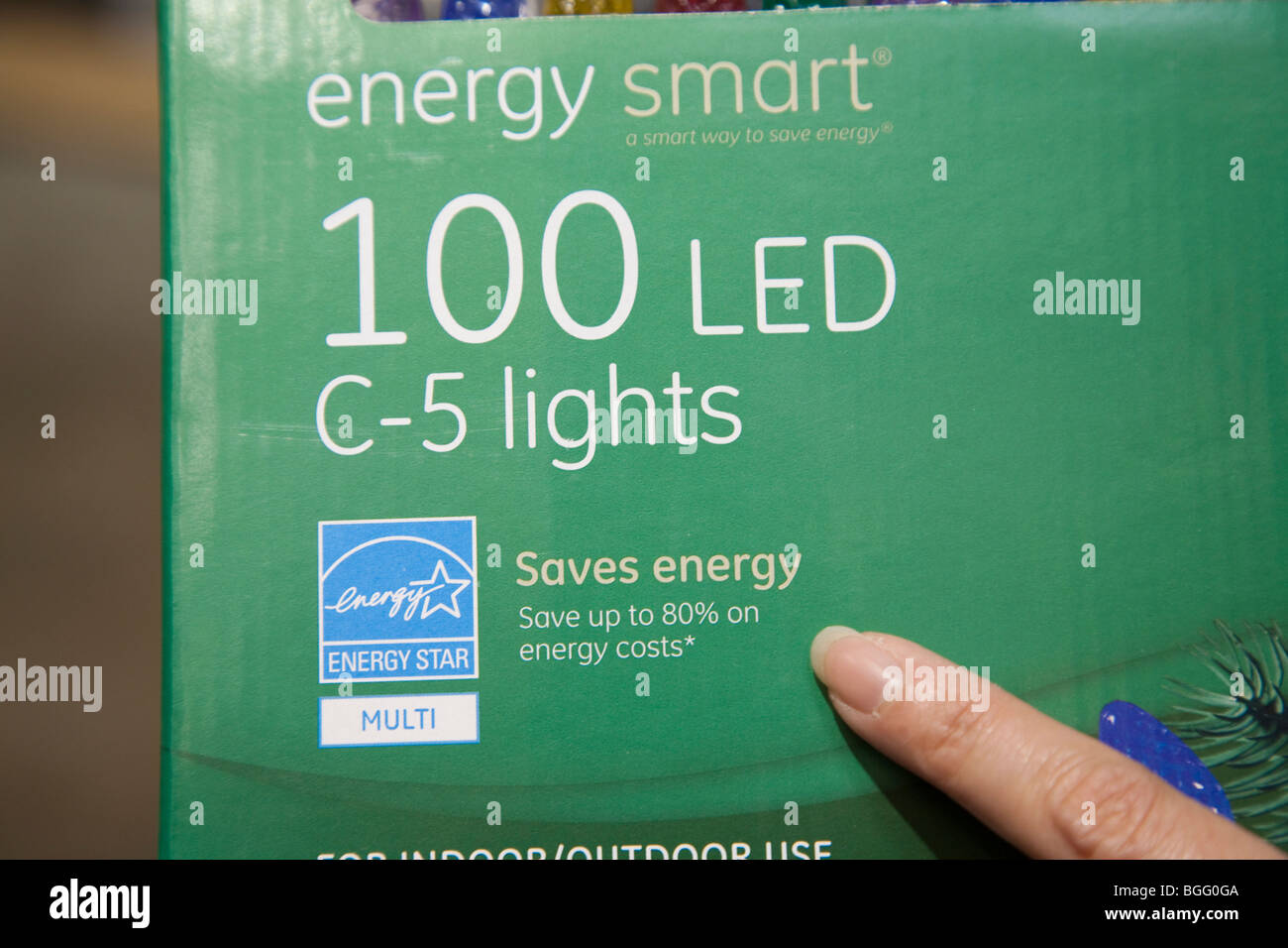 Il dito puntato a risparmiare energia segno sulla vacanza sostenibile pacchetto luci. Foto Stock