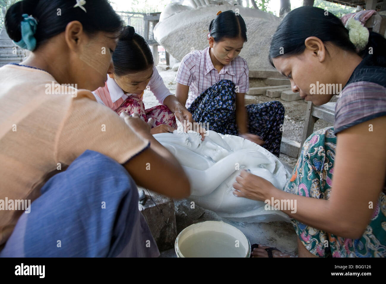 Donne birmane la lucidatura di un marmo statua del Buddha. Mandalay. Myanmar. Foto Stock