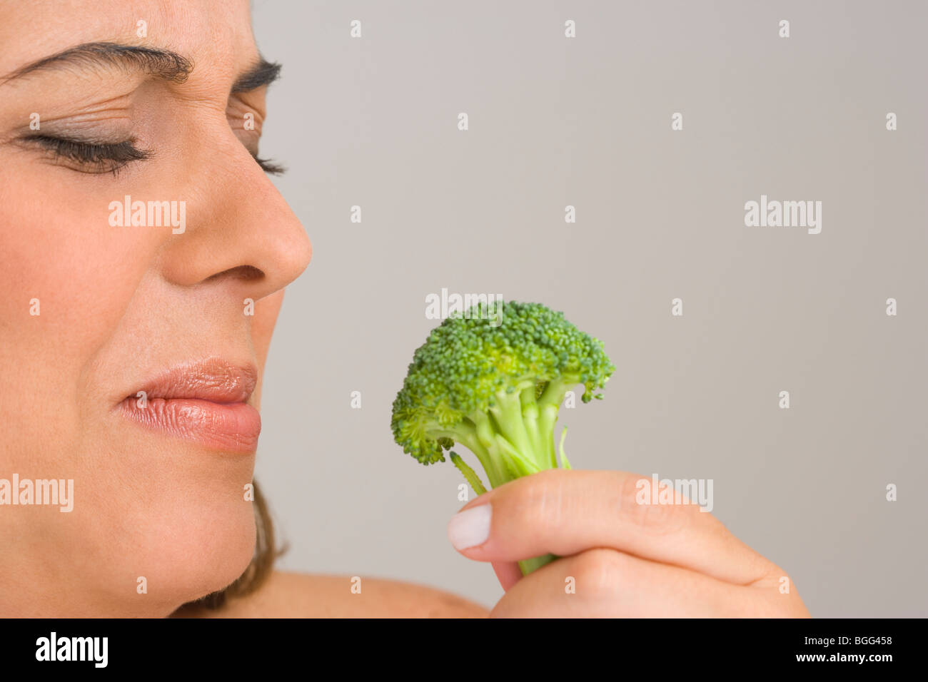 Donna di mangiare un fiorellino di broccoli con disgusto Foto Stock