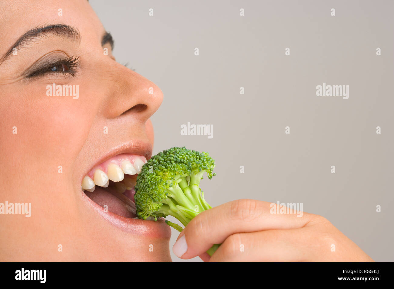 Donna di mangiare un fiorellino di broccoli Foto Stock