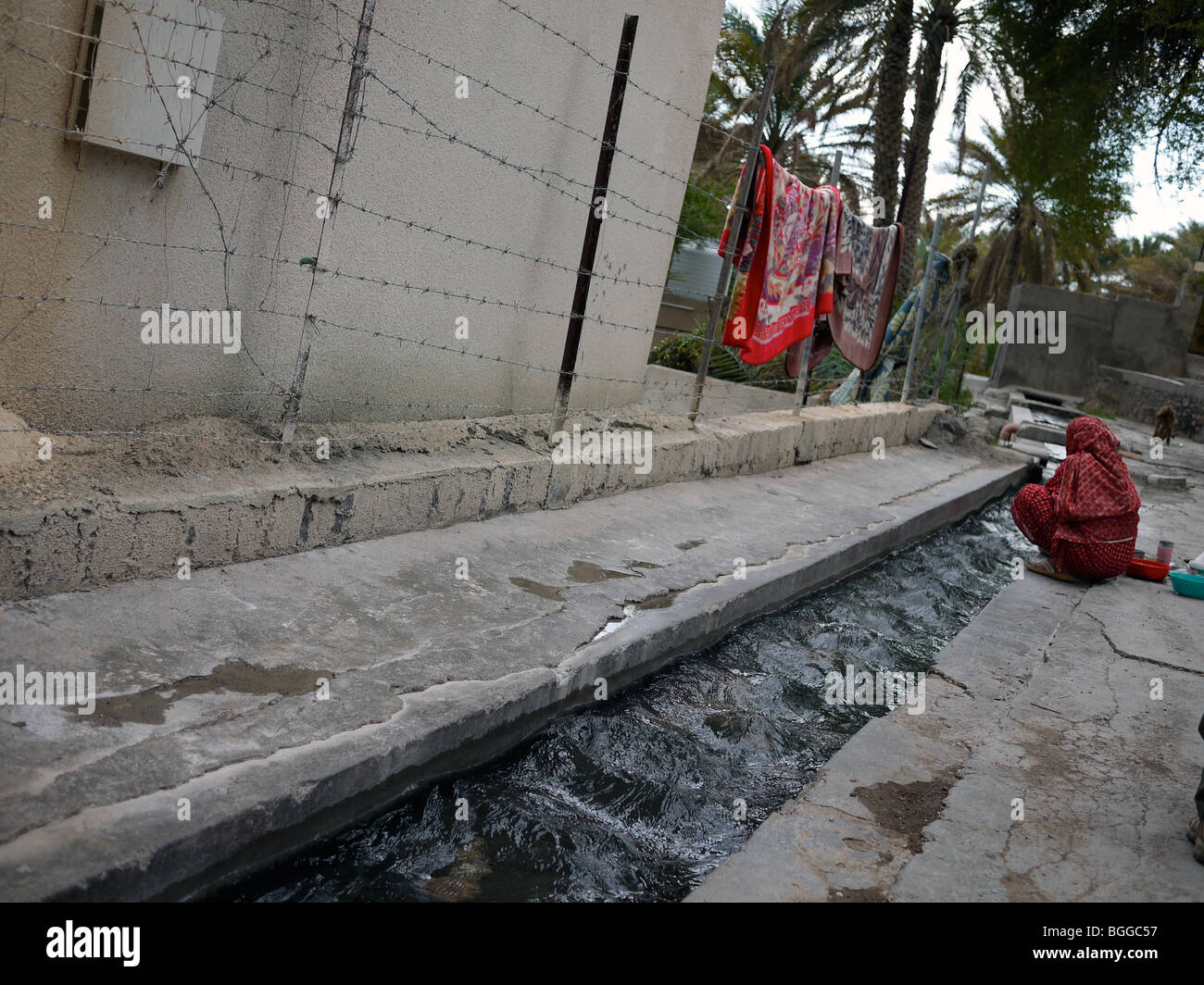 Donna di lavaggio tradizionale in Oman acqua impianto di irrigazione chiamato falaj Foto Stock