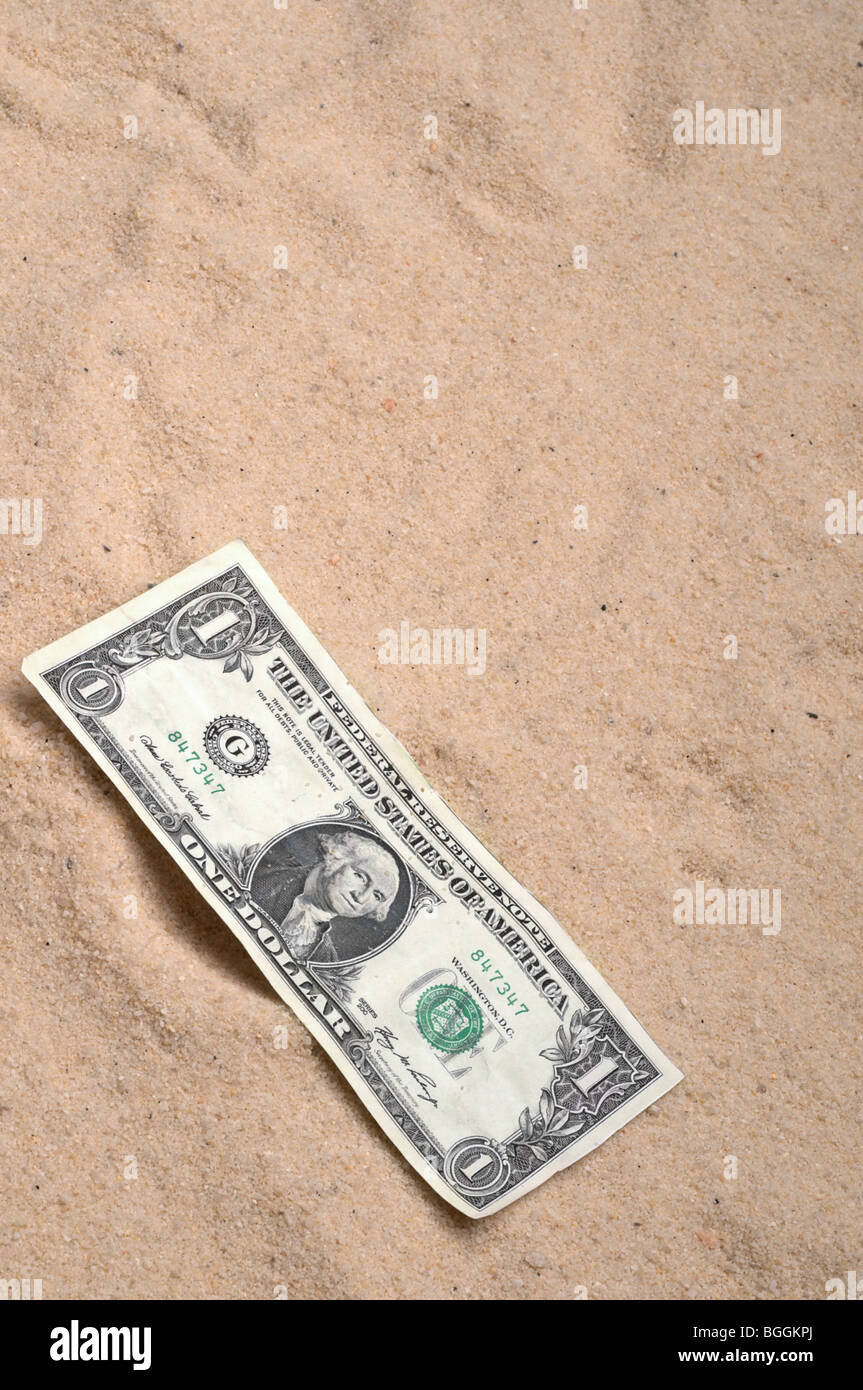 Un dollaro americano Bill sulla sabbia Foto Stock