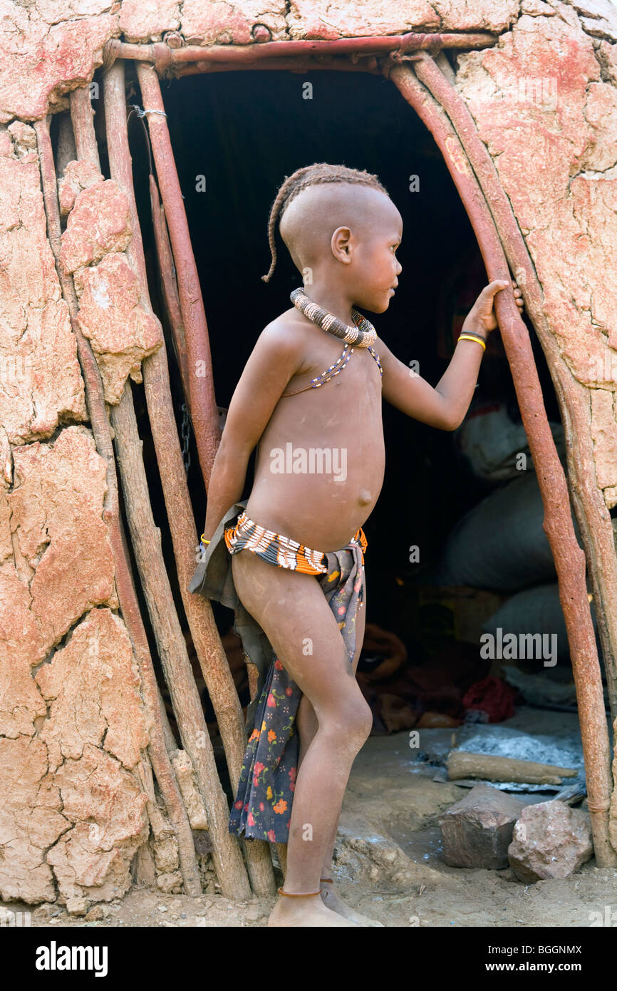 Little Boy del gruppo etnico Owambo in una tradizionale capanna di fango, Opuwo, Namibia Foto Stock