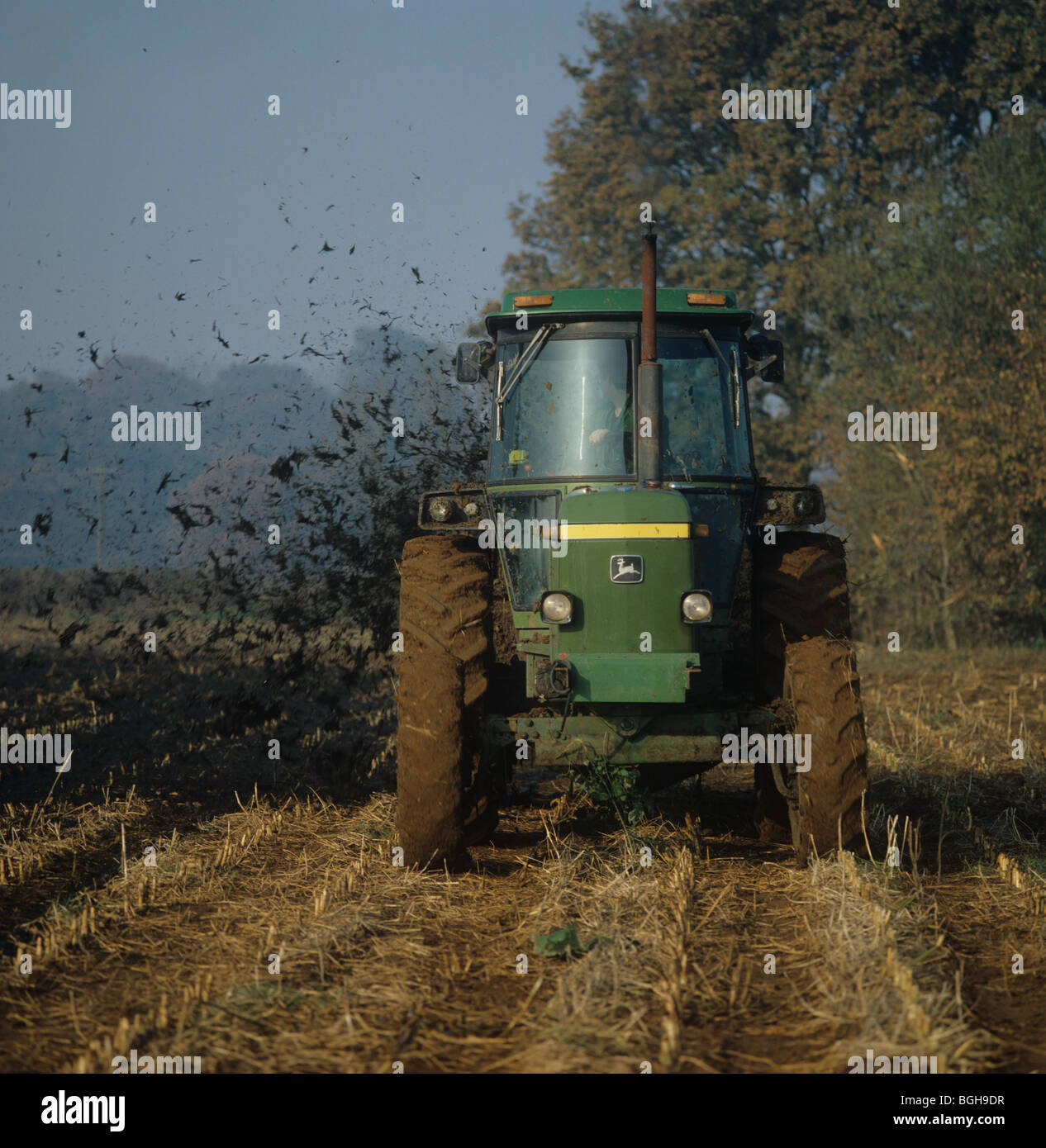 Trattore John Deere diffusione muck sulla stoppia mais prima di coltivazione e di reimpianto Foto Stock