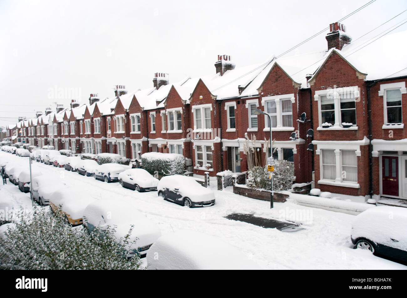 La linea di automobili e case in Boundary Road, Colliers Wood, a sud-ovest di Londra, coperto di neve profonda Foto Stock